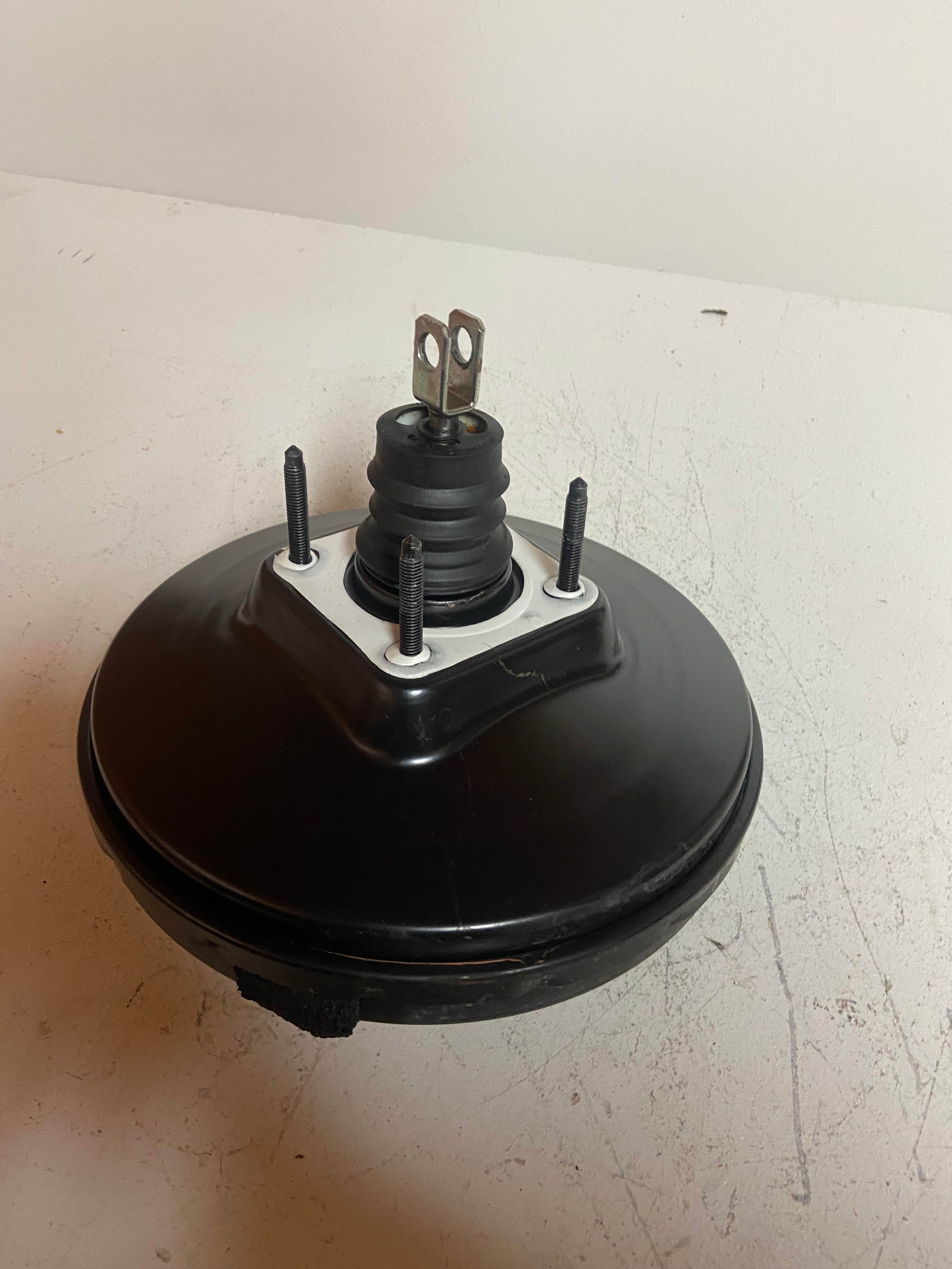Black power brake booster with central valve stem and three mounting posts