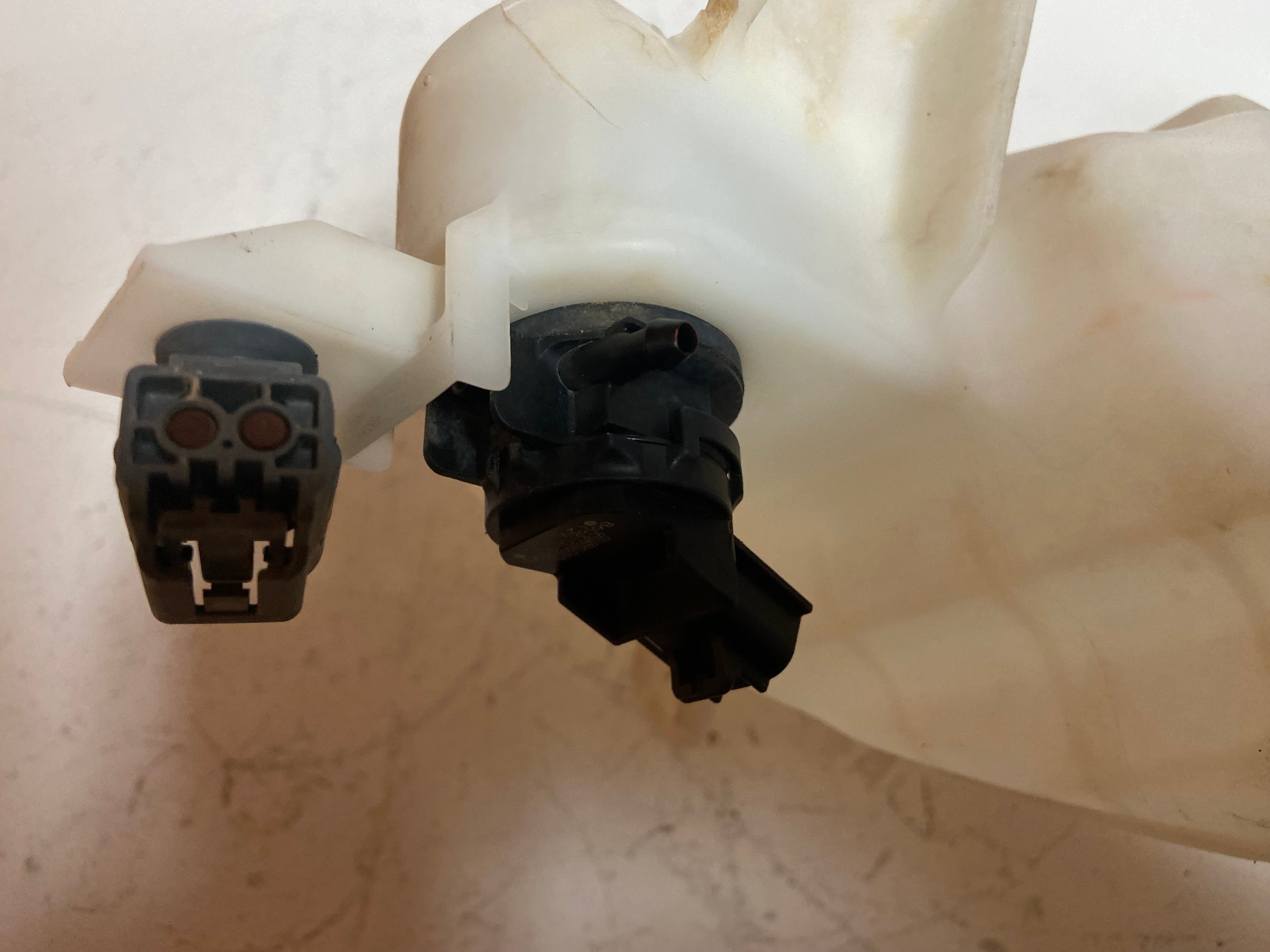 Washer fluid reservoir tank with black nozzle connector and electrical plug