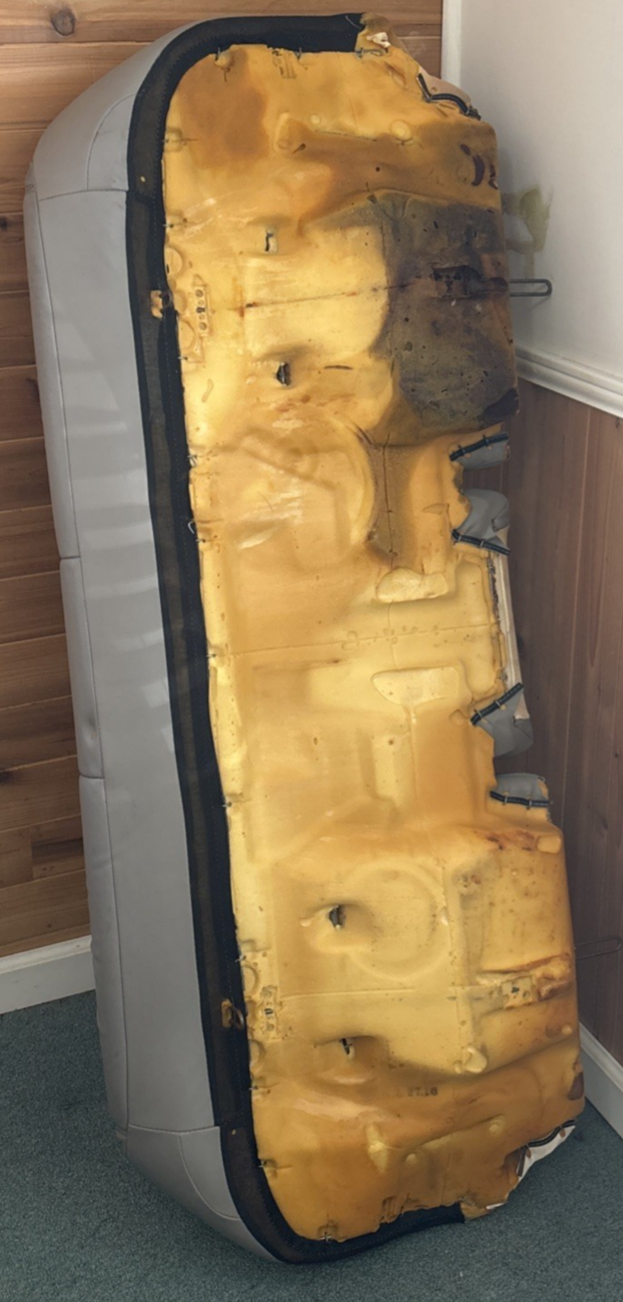 Defective air mattress with visible tears and damage on a white appliance.