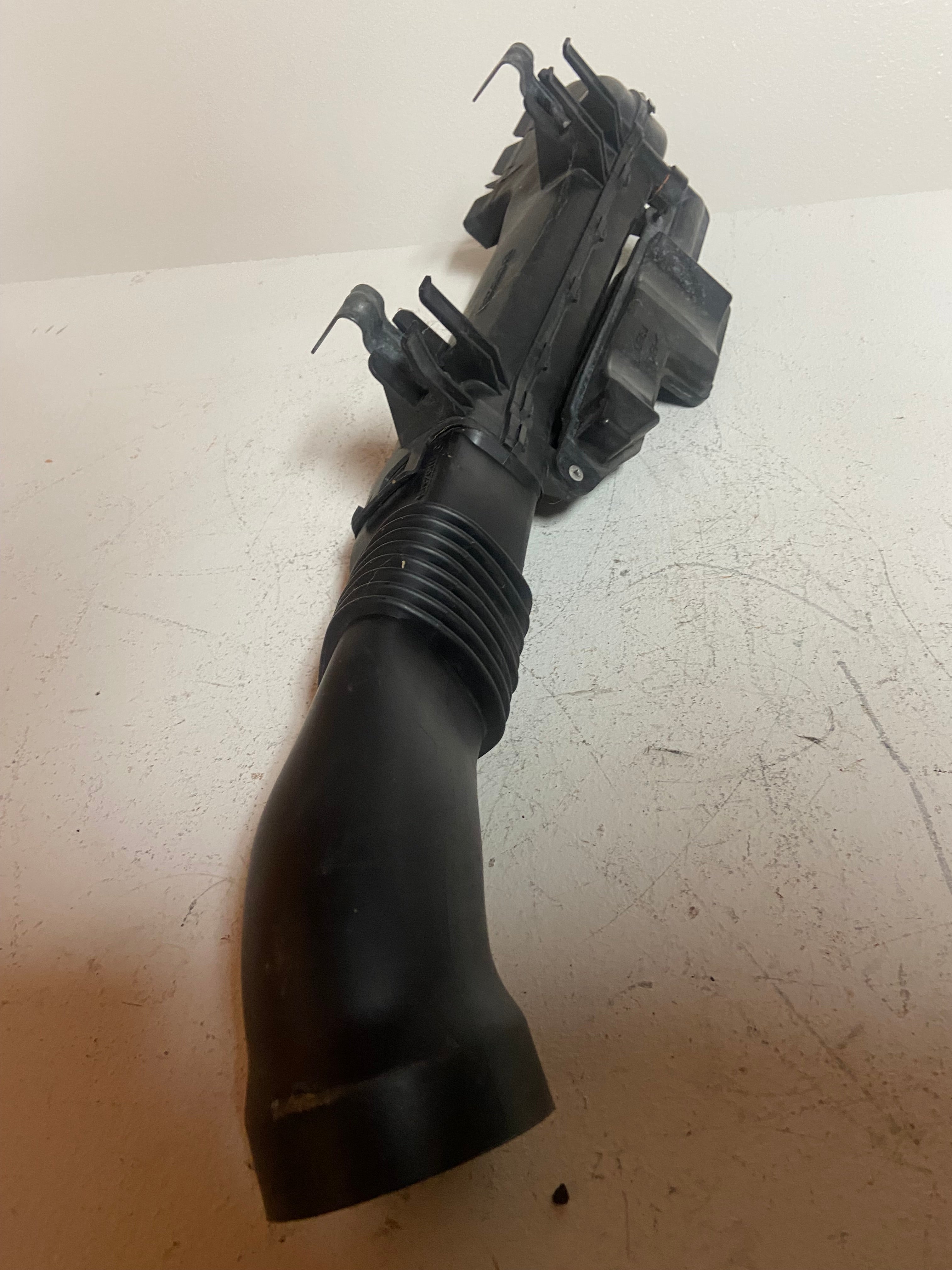 Black plastic air intake duct with ribbed intake hose and connector housing
