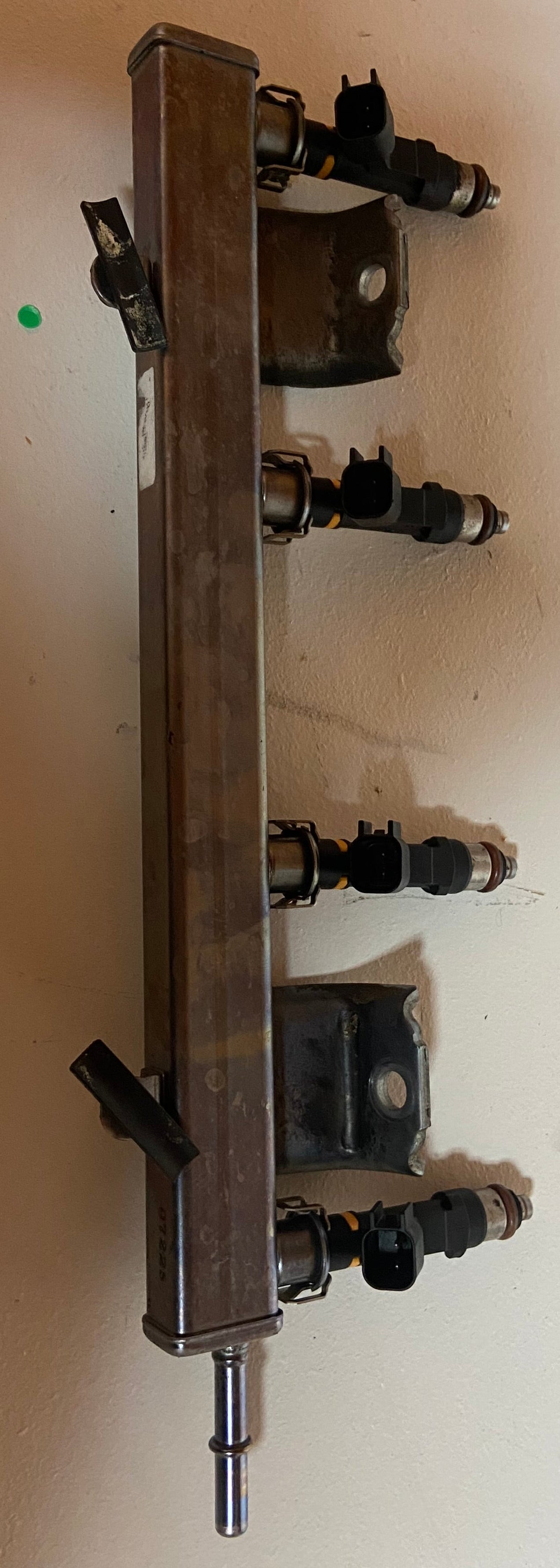 Long metal engine fuel rail with four black injector connectors and end fitting