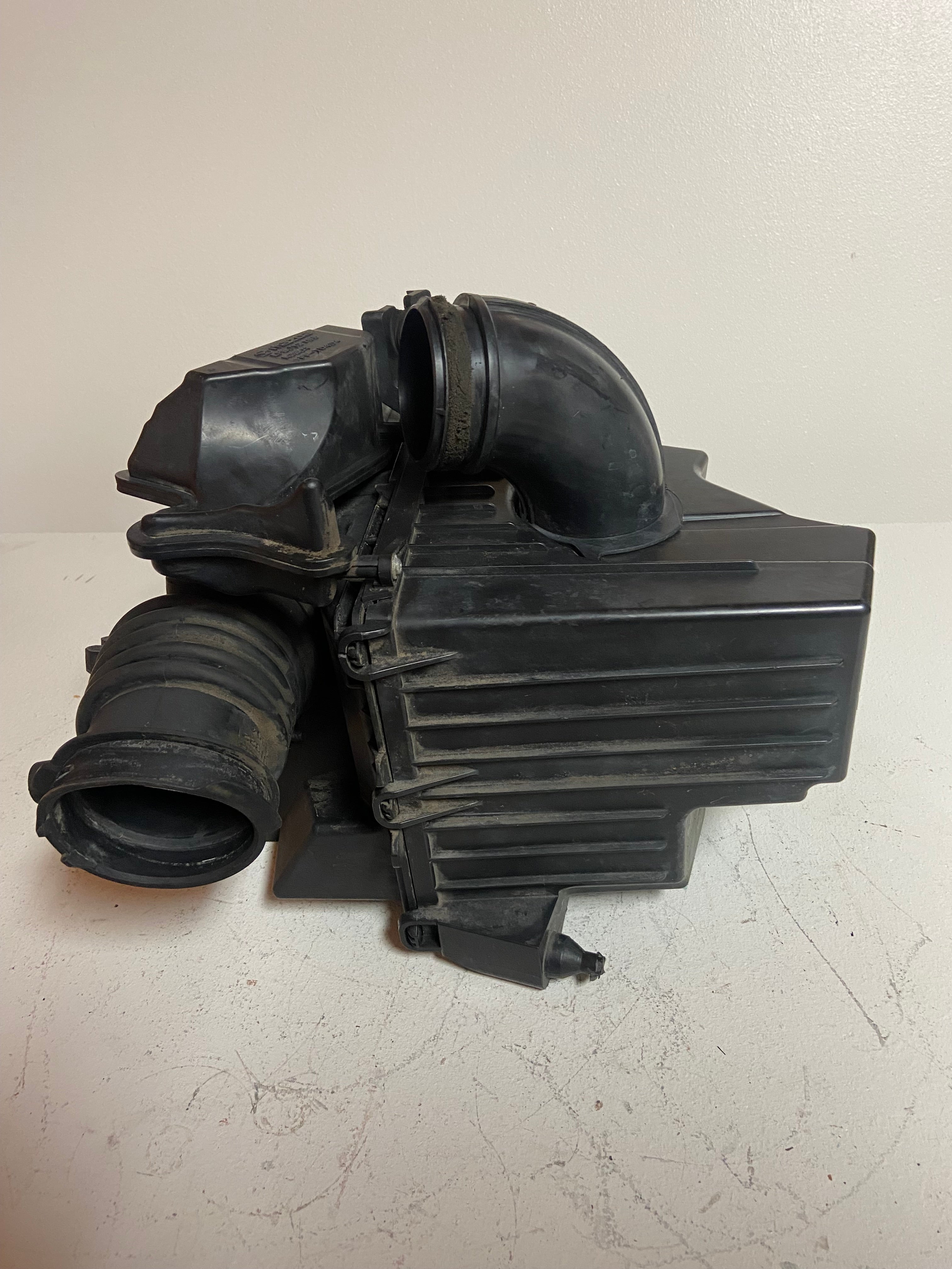 Black plastic air intake housing with large intake duct and ribbed air tube