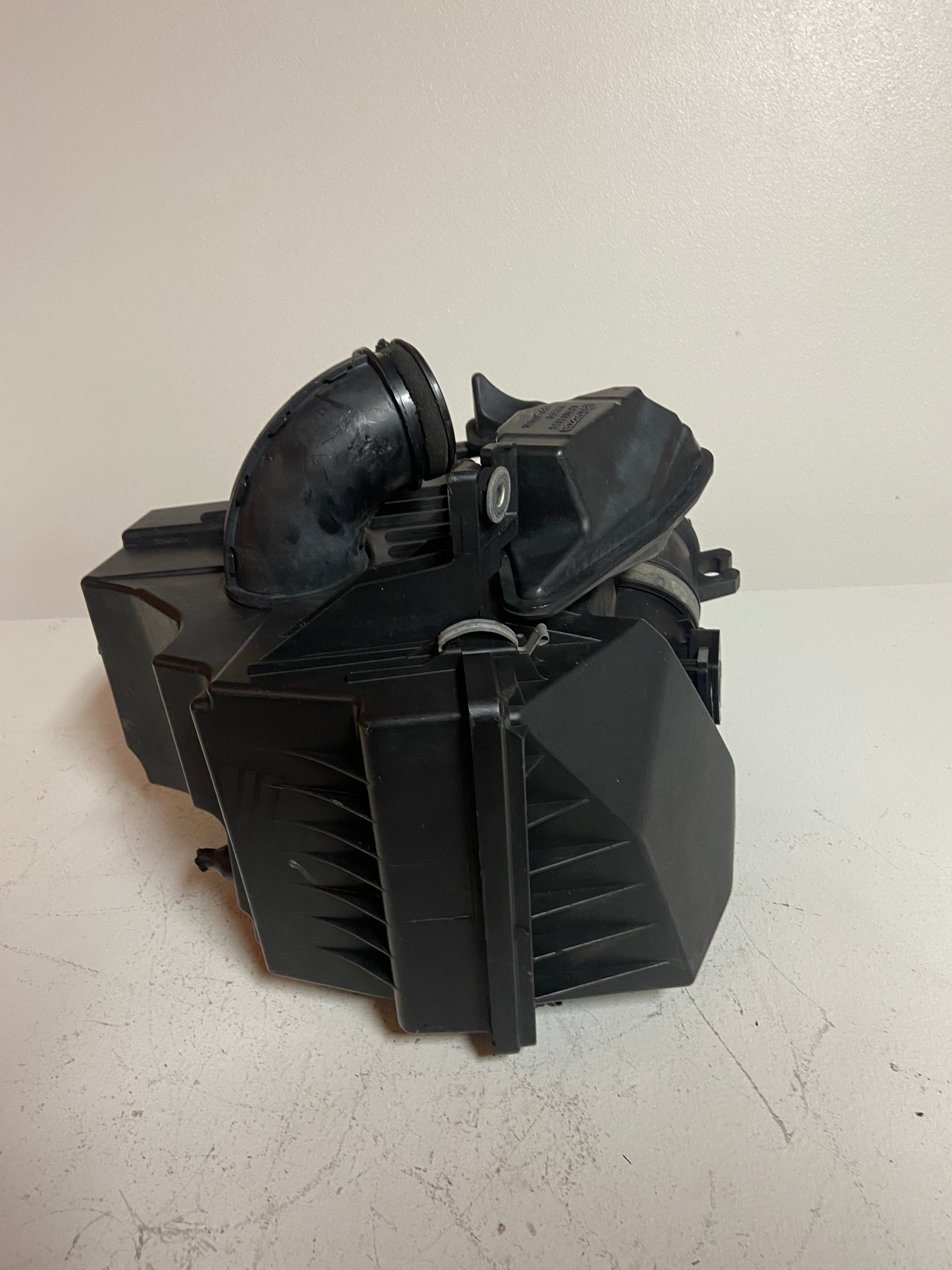 Black engine air cleaner filter box with intake duct and circular air opening