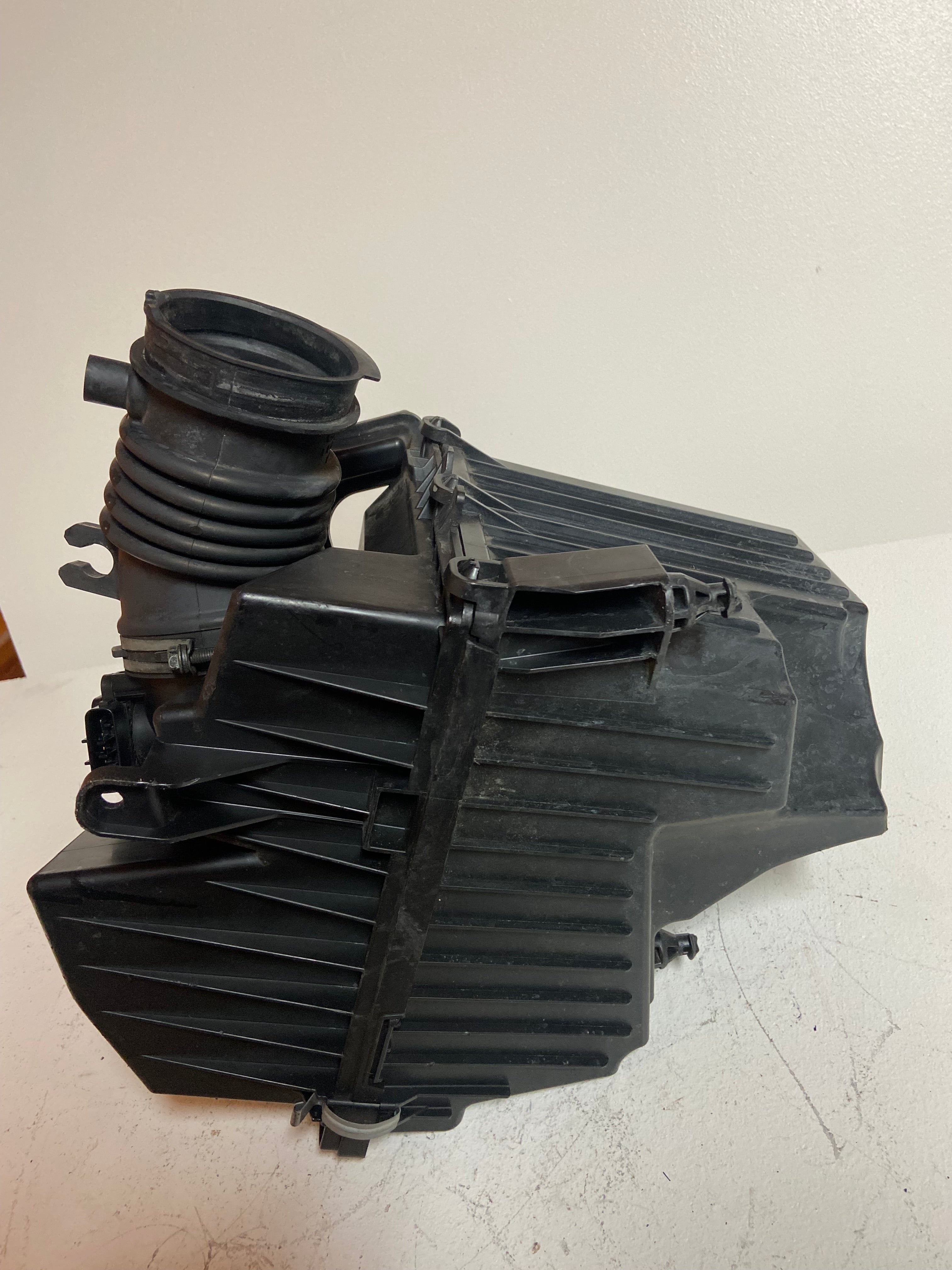 Air intake filter box housing with curved duct and ribbed air intake tube