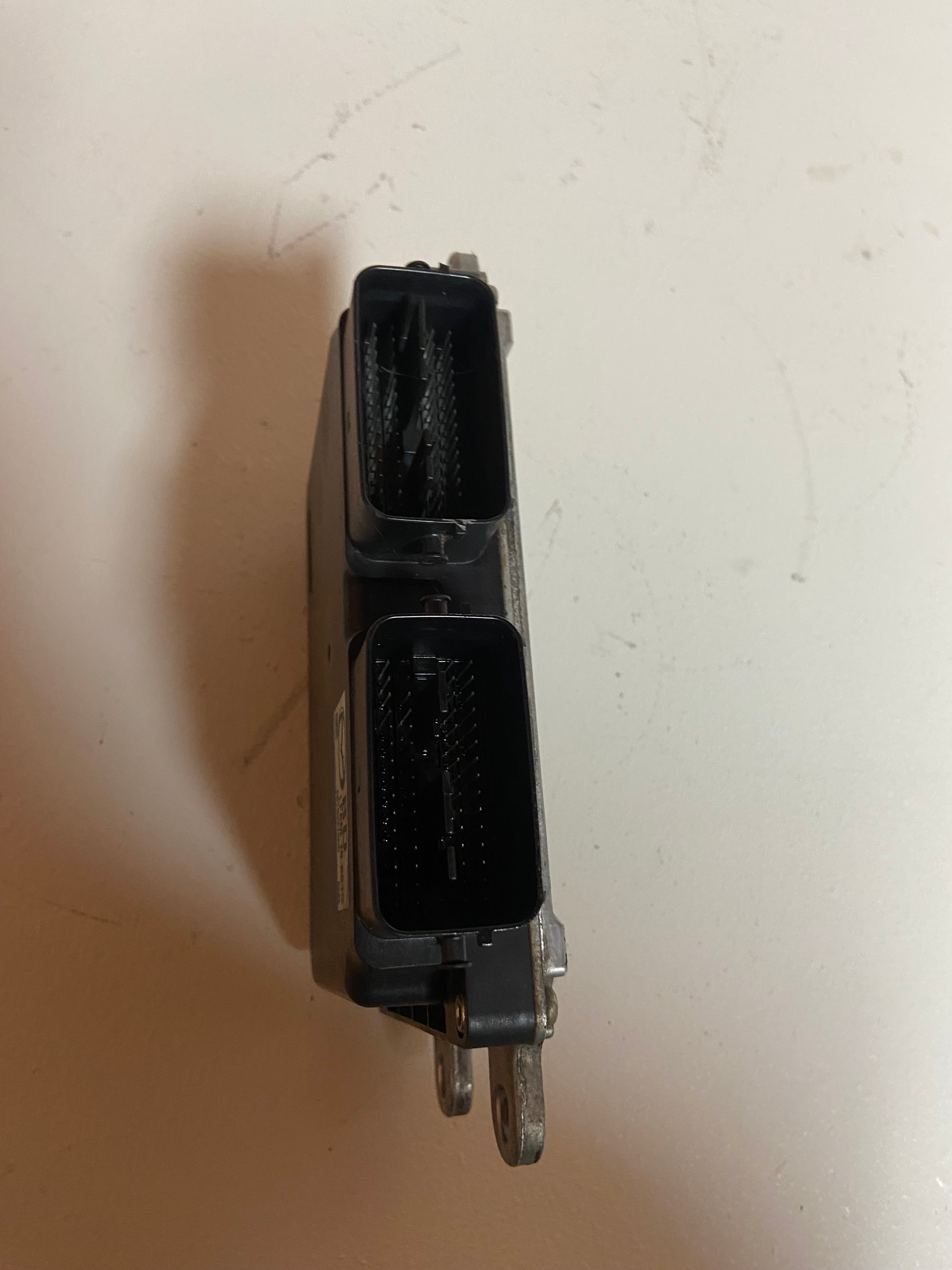 Black engine control module with rectangular electrical connector and metal mounting pin