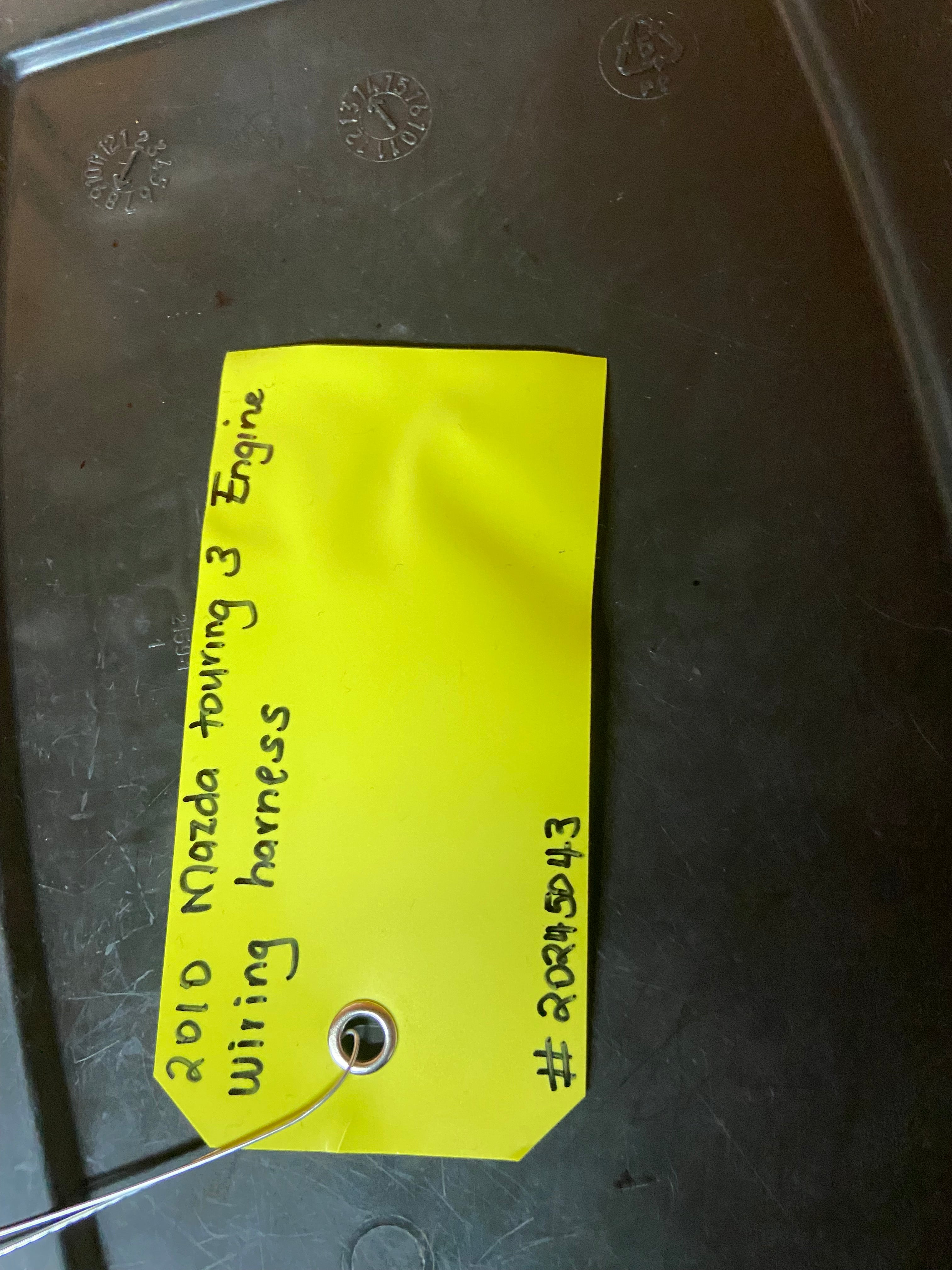 Automotive wiring harness label on black cover with blue and gray connector ports.