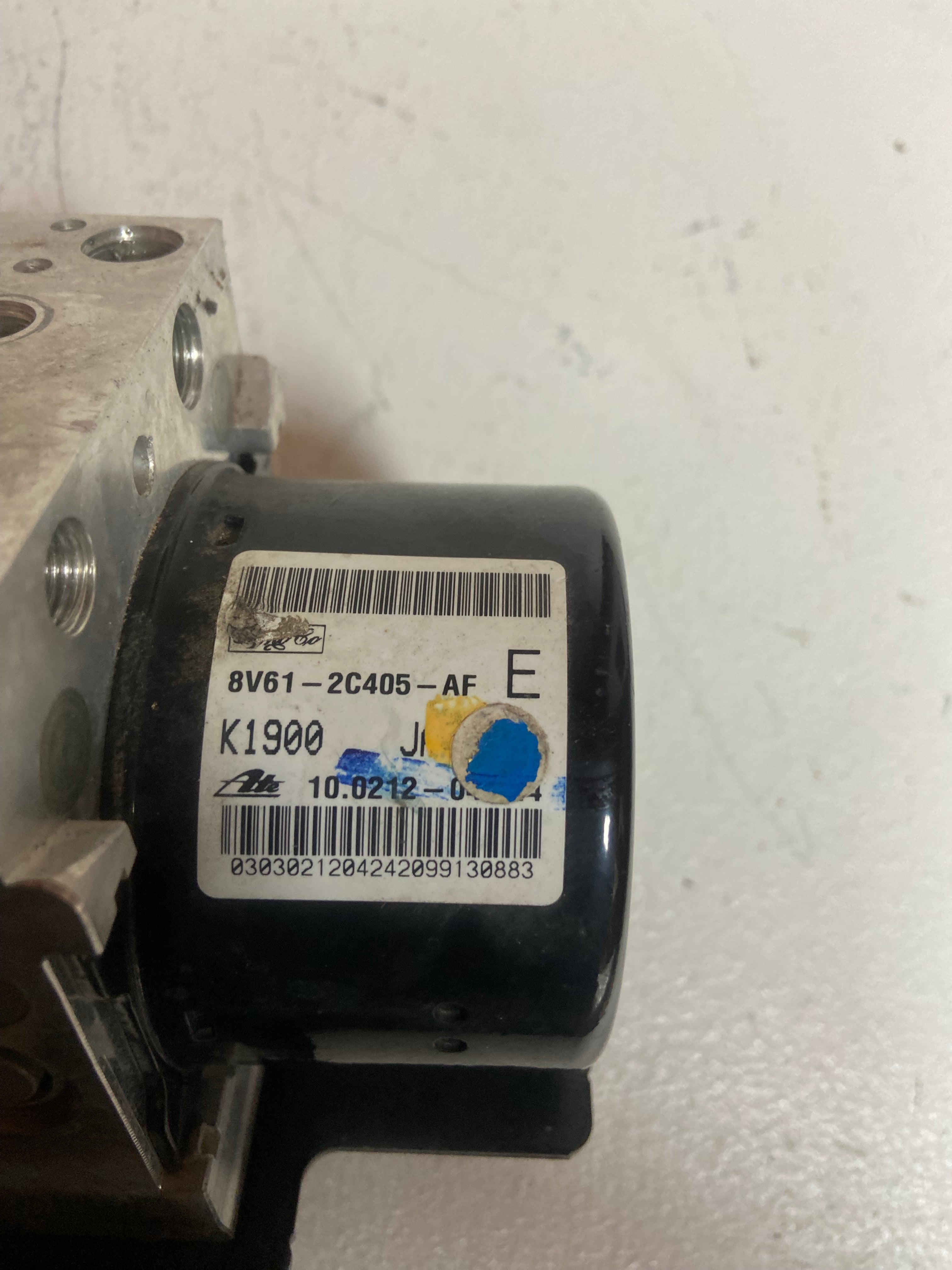 ABS brake pump control module with barcode label and metal mounting plate.