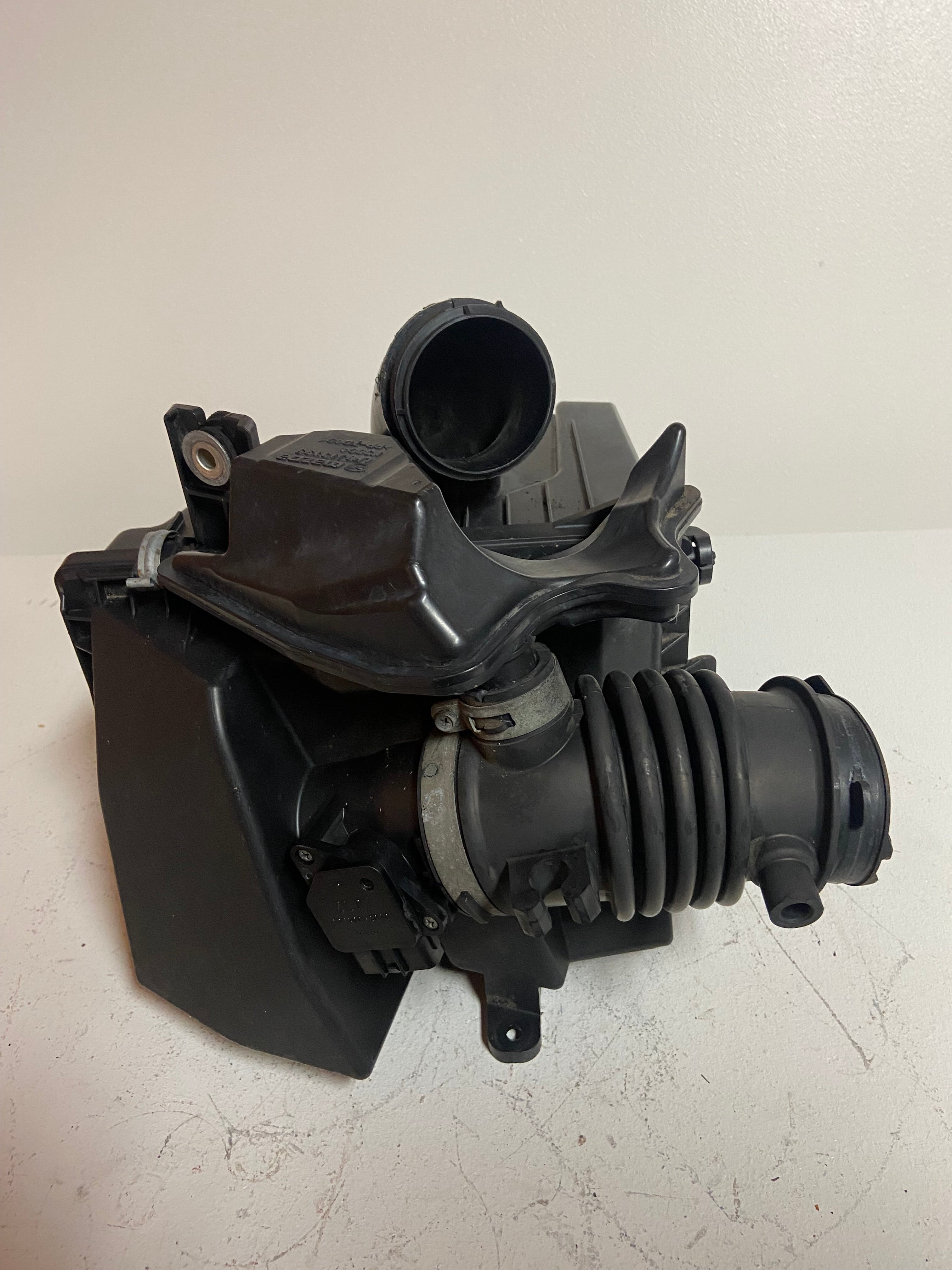 Black intake air cleaner housing with attached corrugated duct and round inlet
