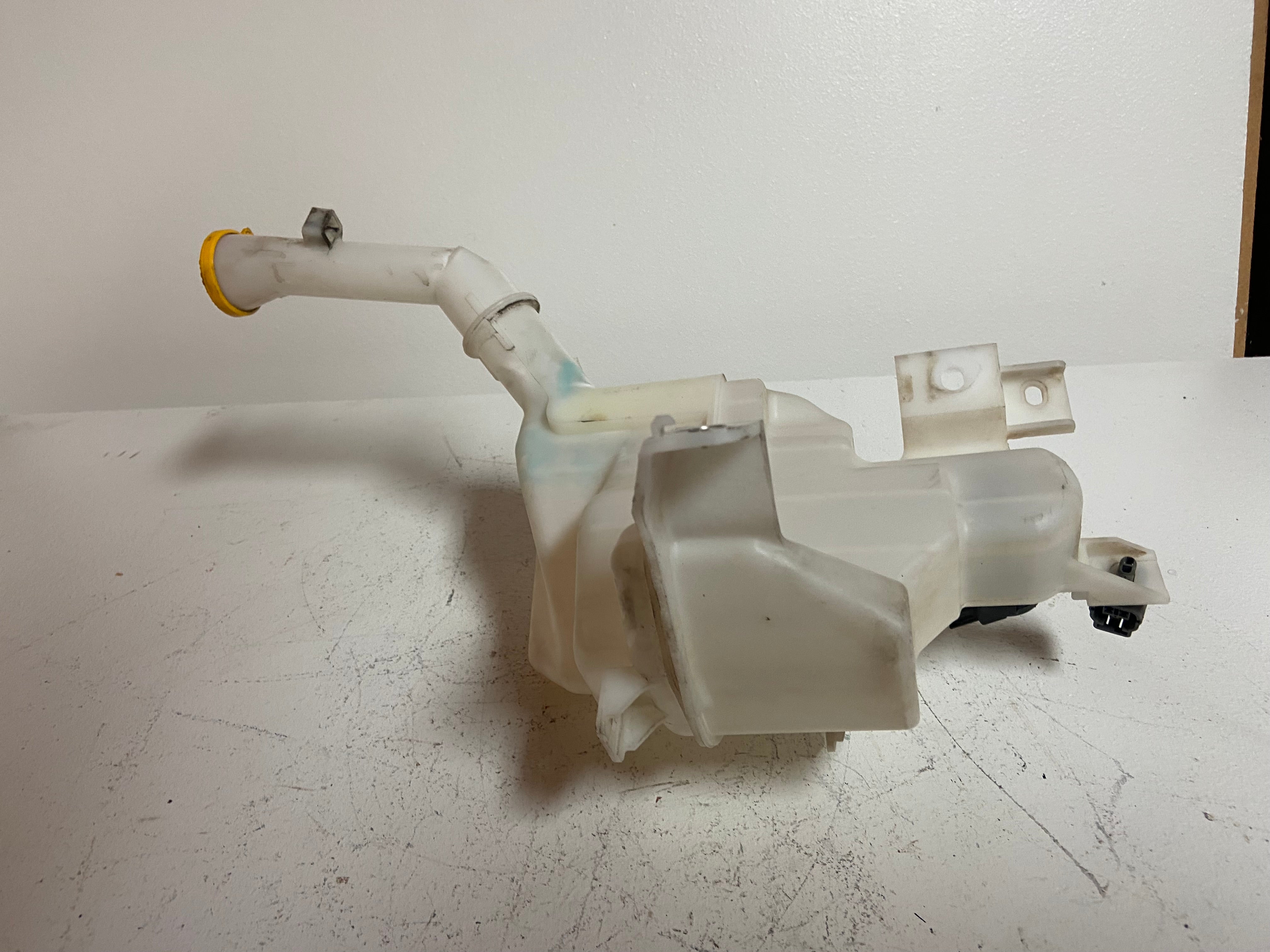 Washer fluid reservoir tank with white hose and angled outlet pipe