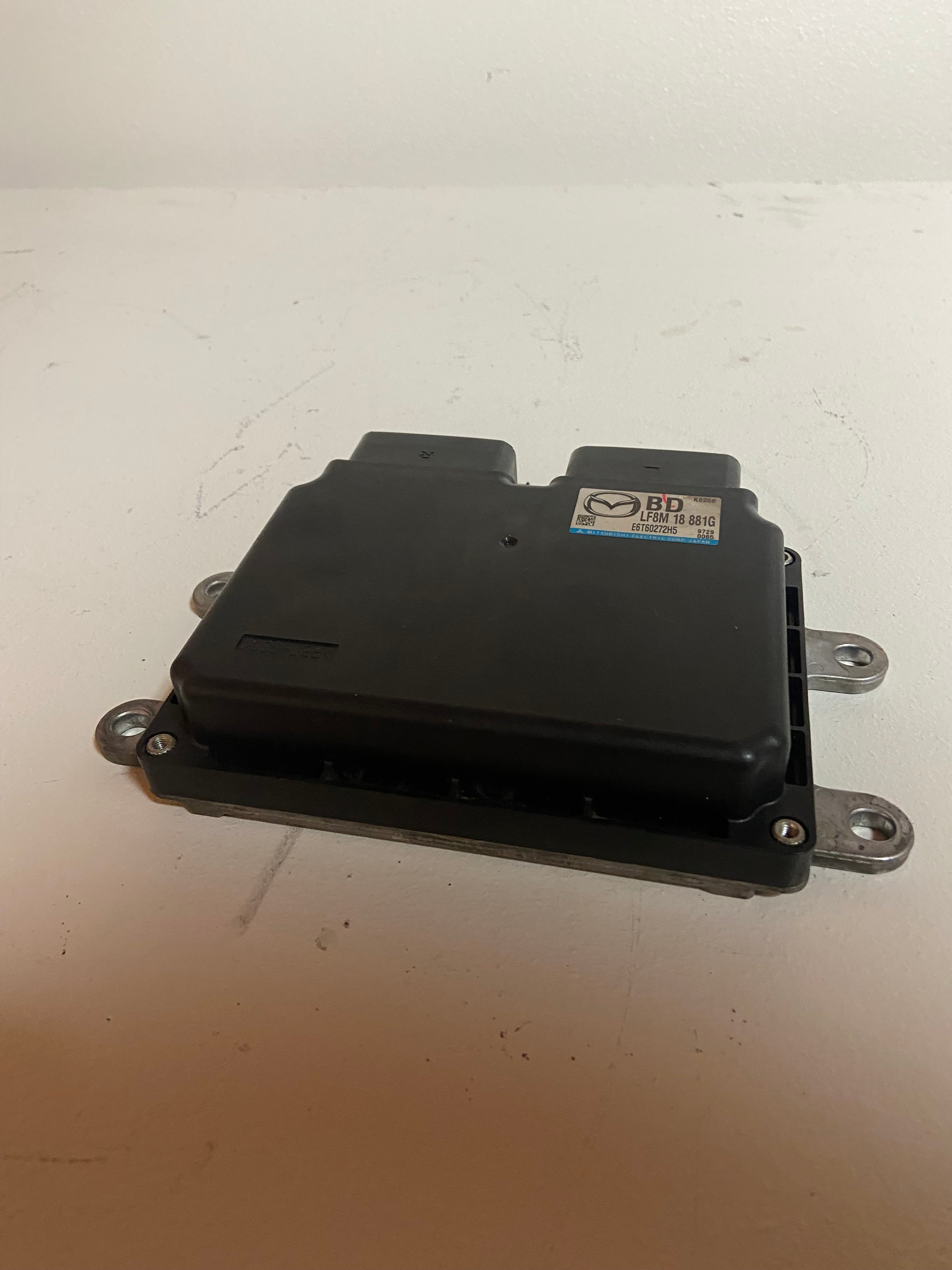 Black engine control unit with side label and two metal mounting brackets