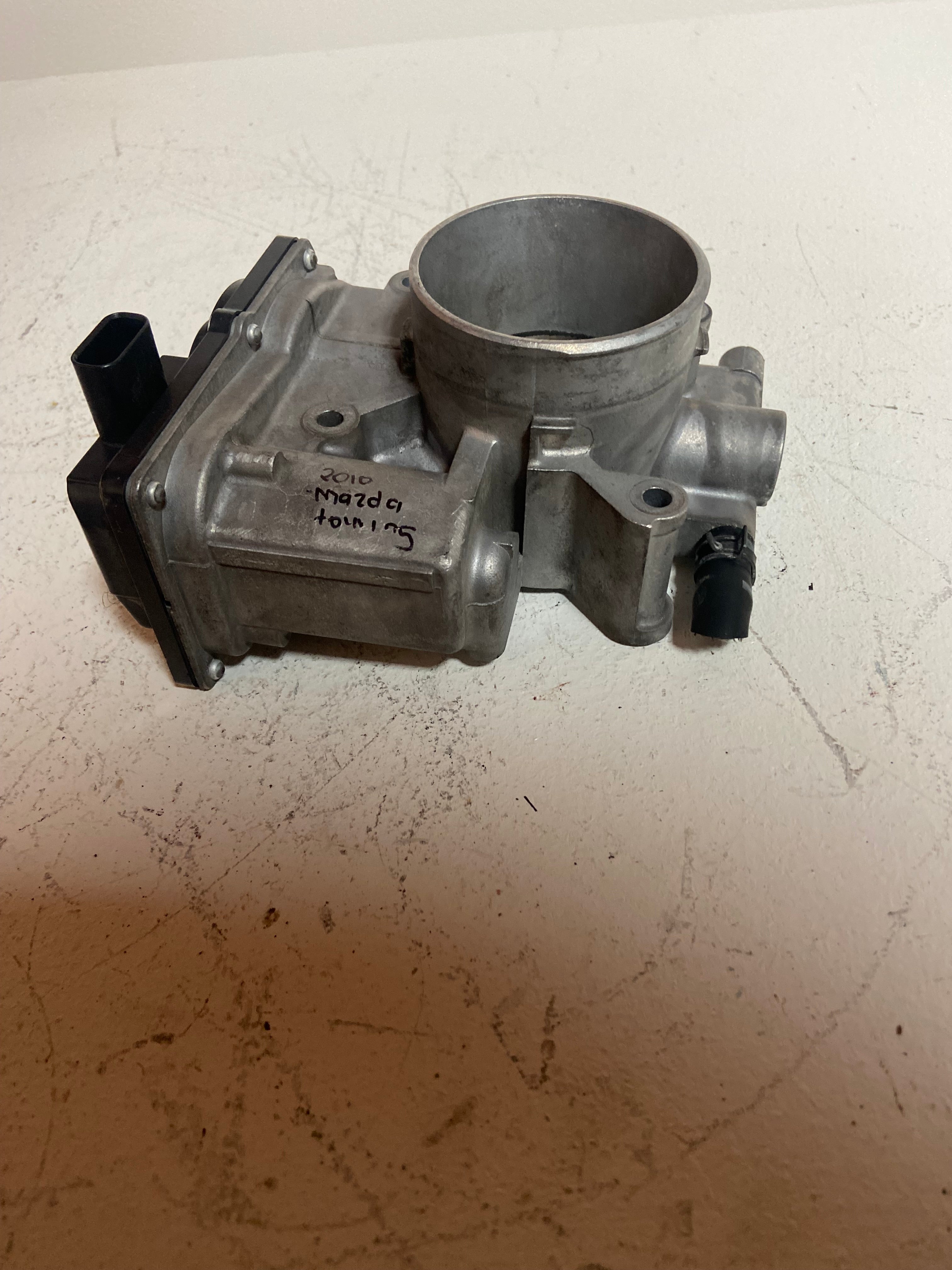Throttle body with metal inlet bore and attached vacuum/connector ports