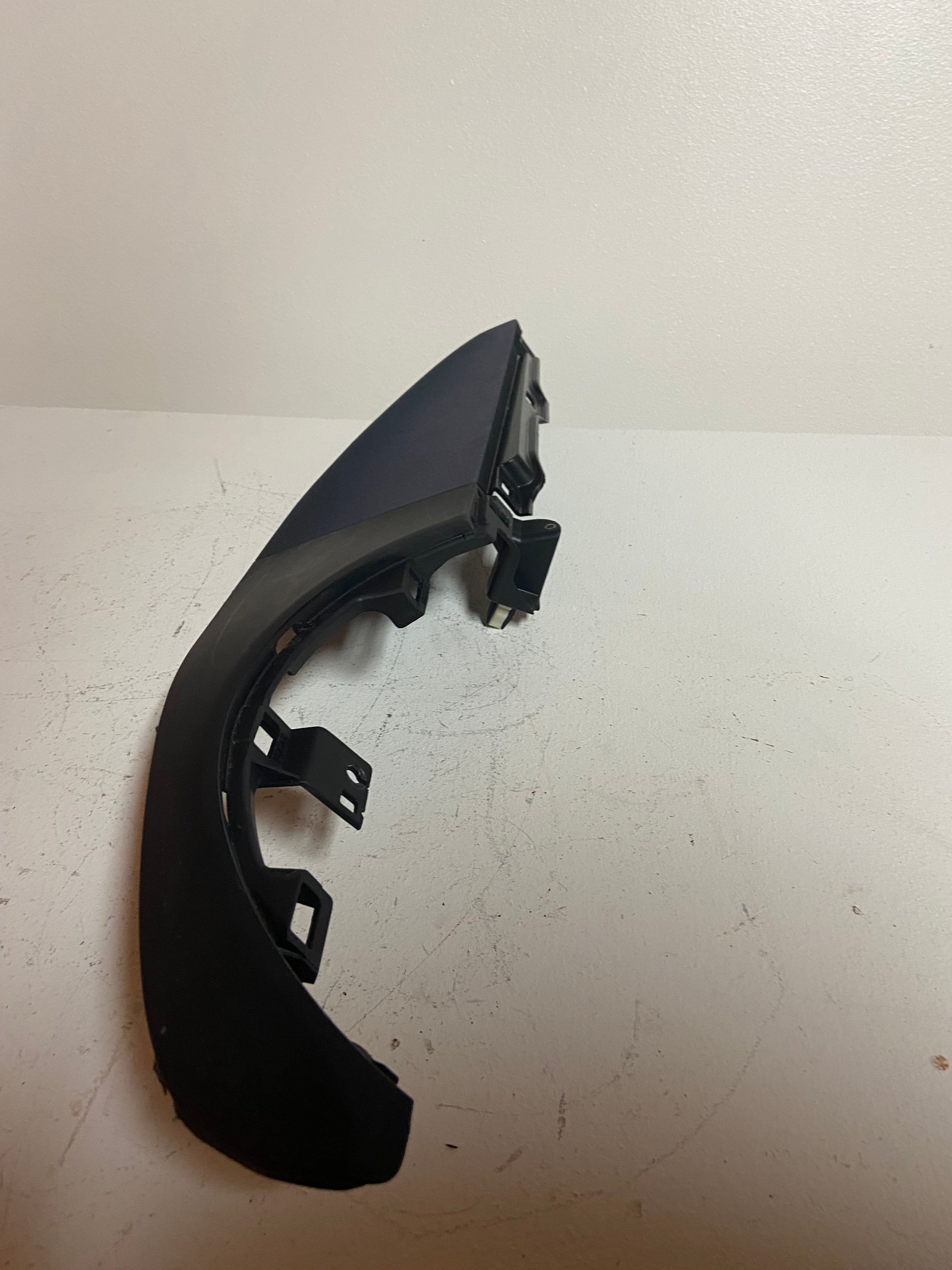 Curved dark instrument cluster trim bezel with visible brackets on underside