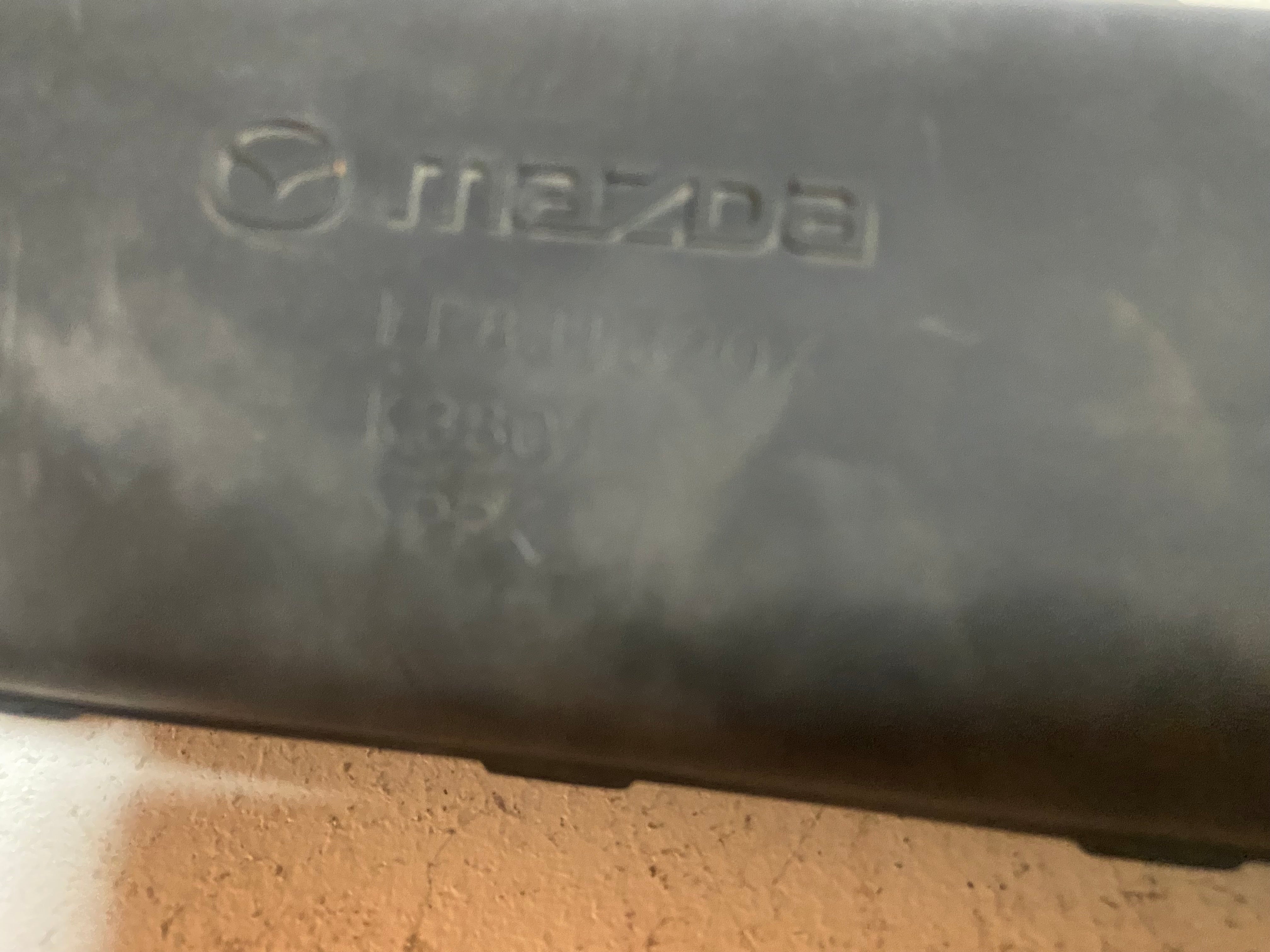 Black plastic air intake duct with Mazda logo embossed