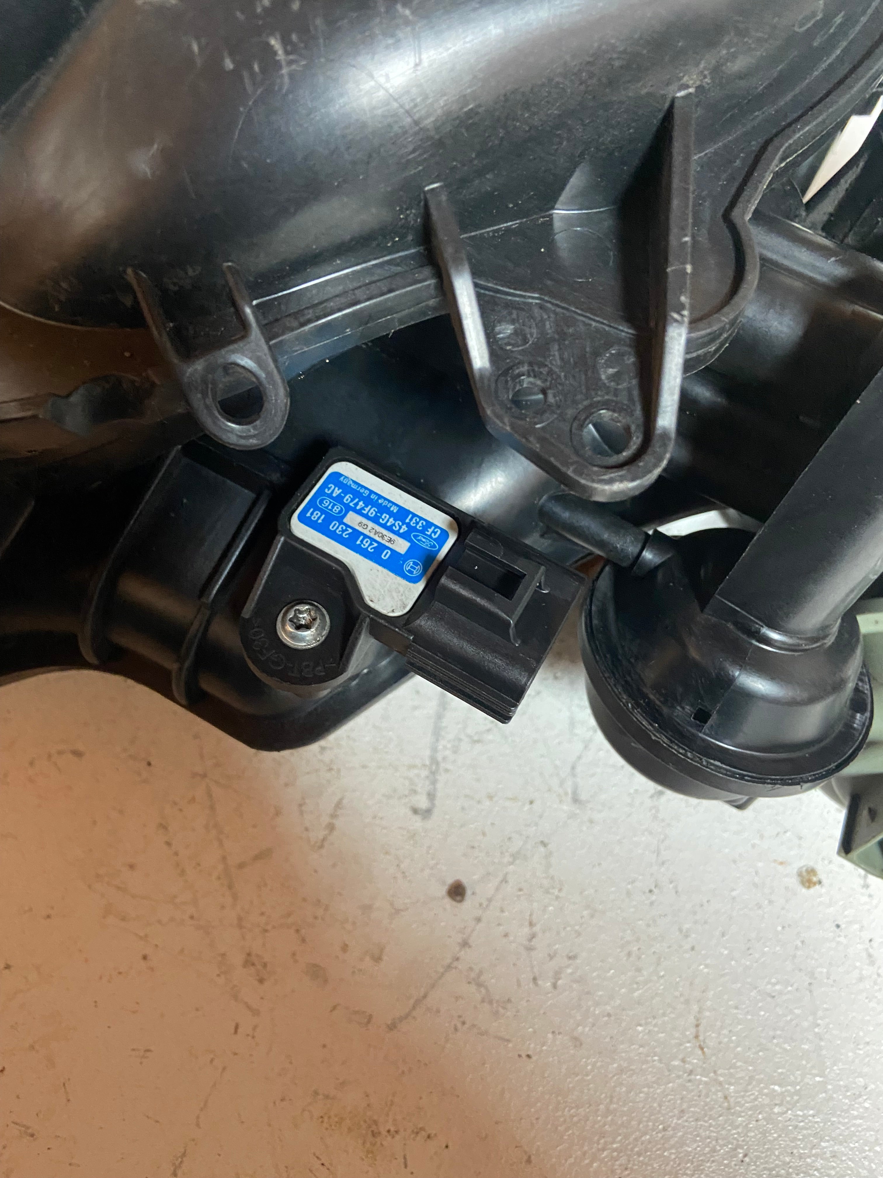 Engine air intake manifold detail view with vacuum ports and electrical connector