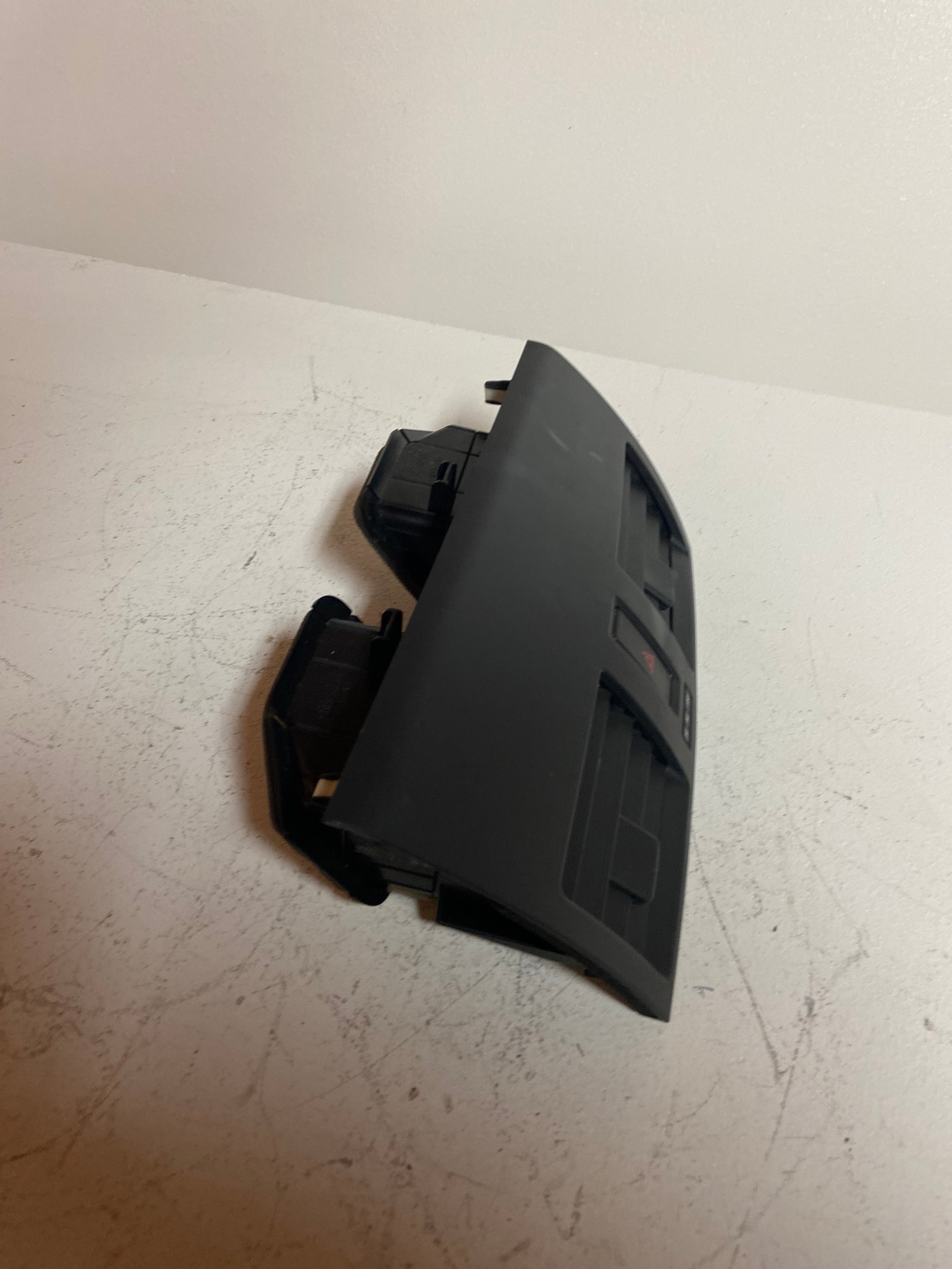 Black center dashboard air vent and hazard switch module, partial view from side