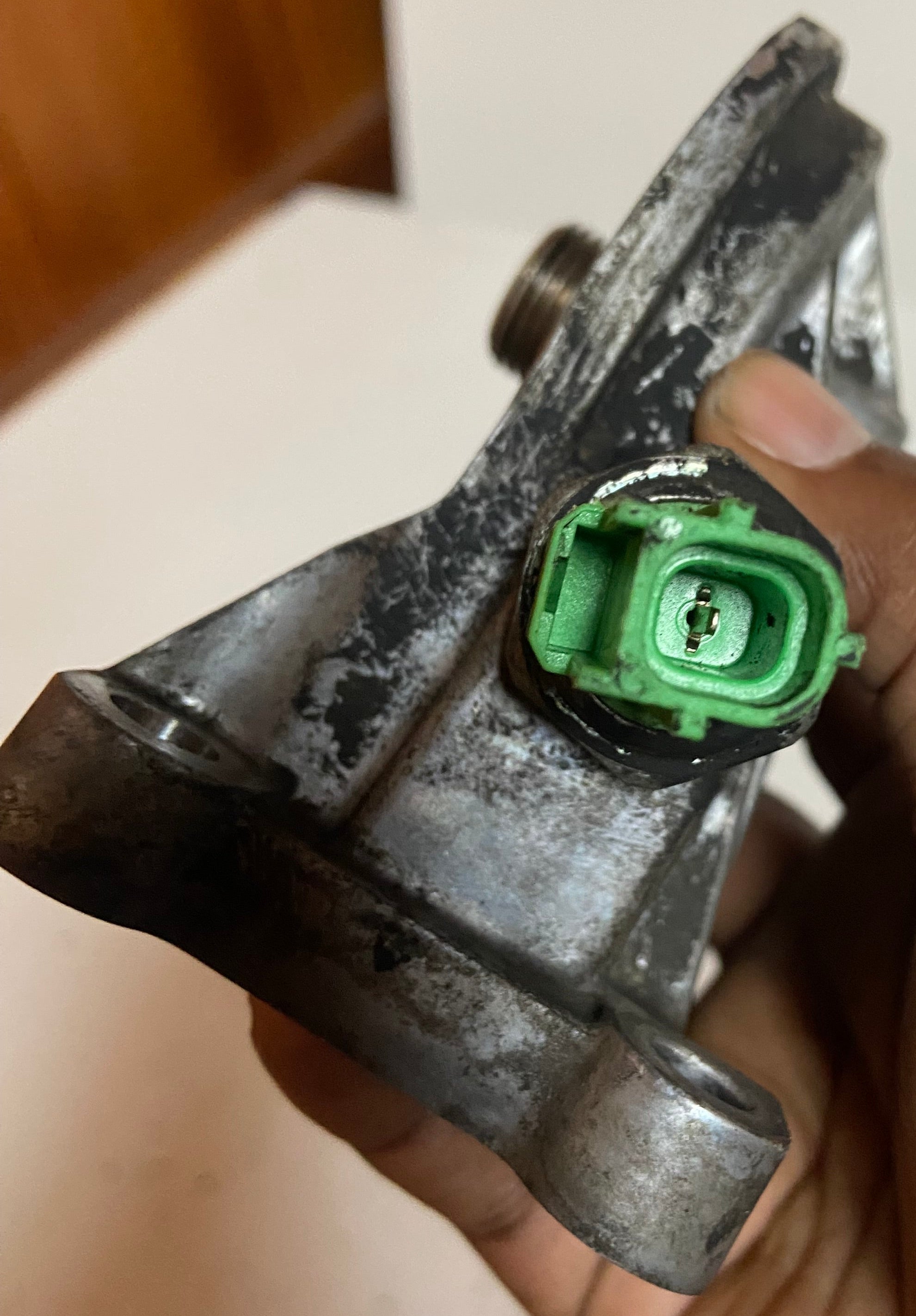 Engine oil filter adapter housing with green sensor connector and mounting bolts