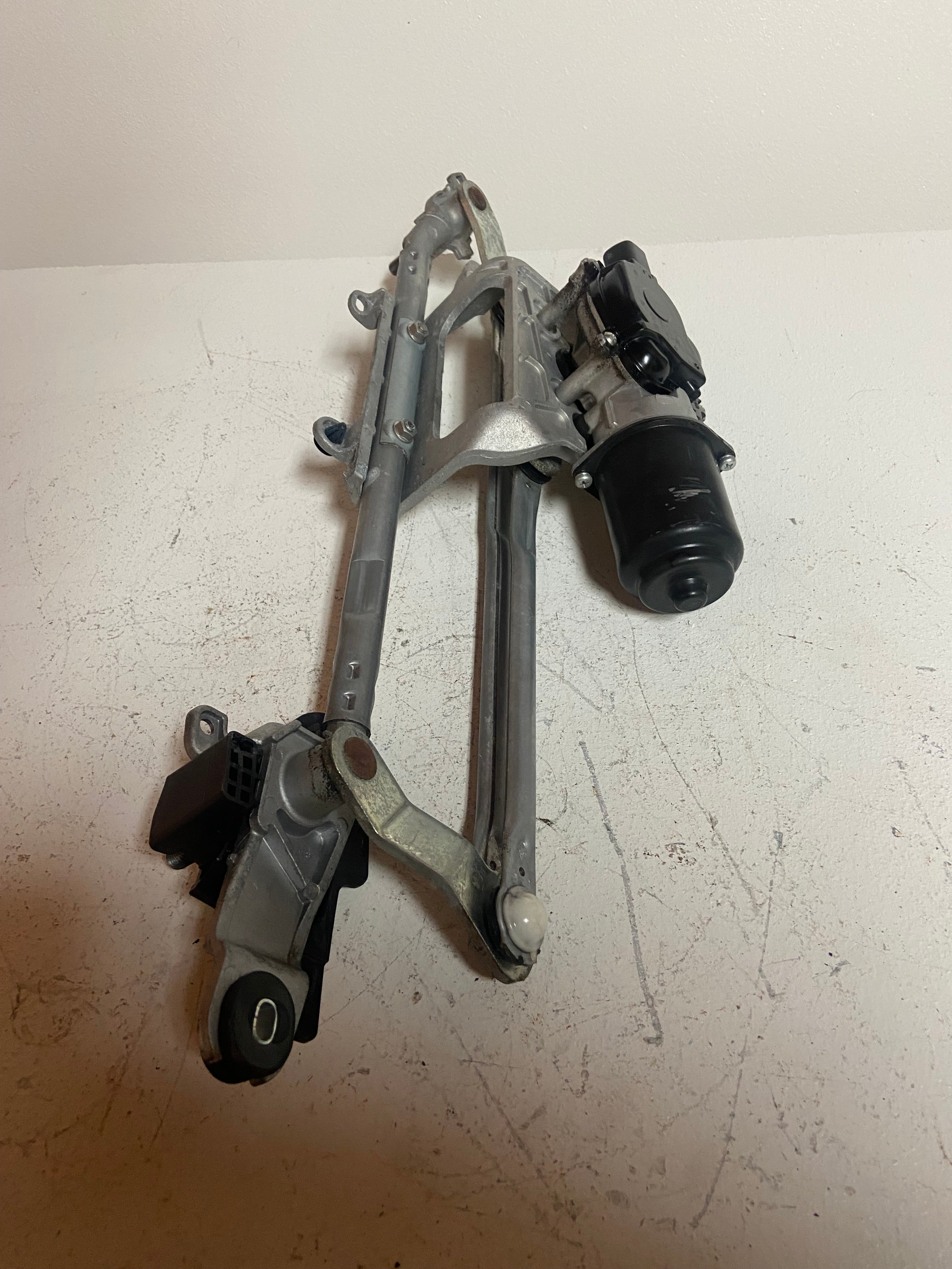 Windshield wiper motor linkage assembly with metal arms and black cylindrical motor