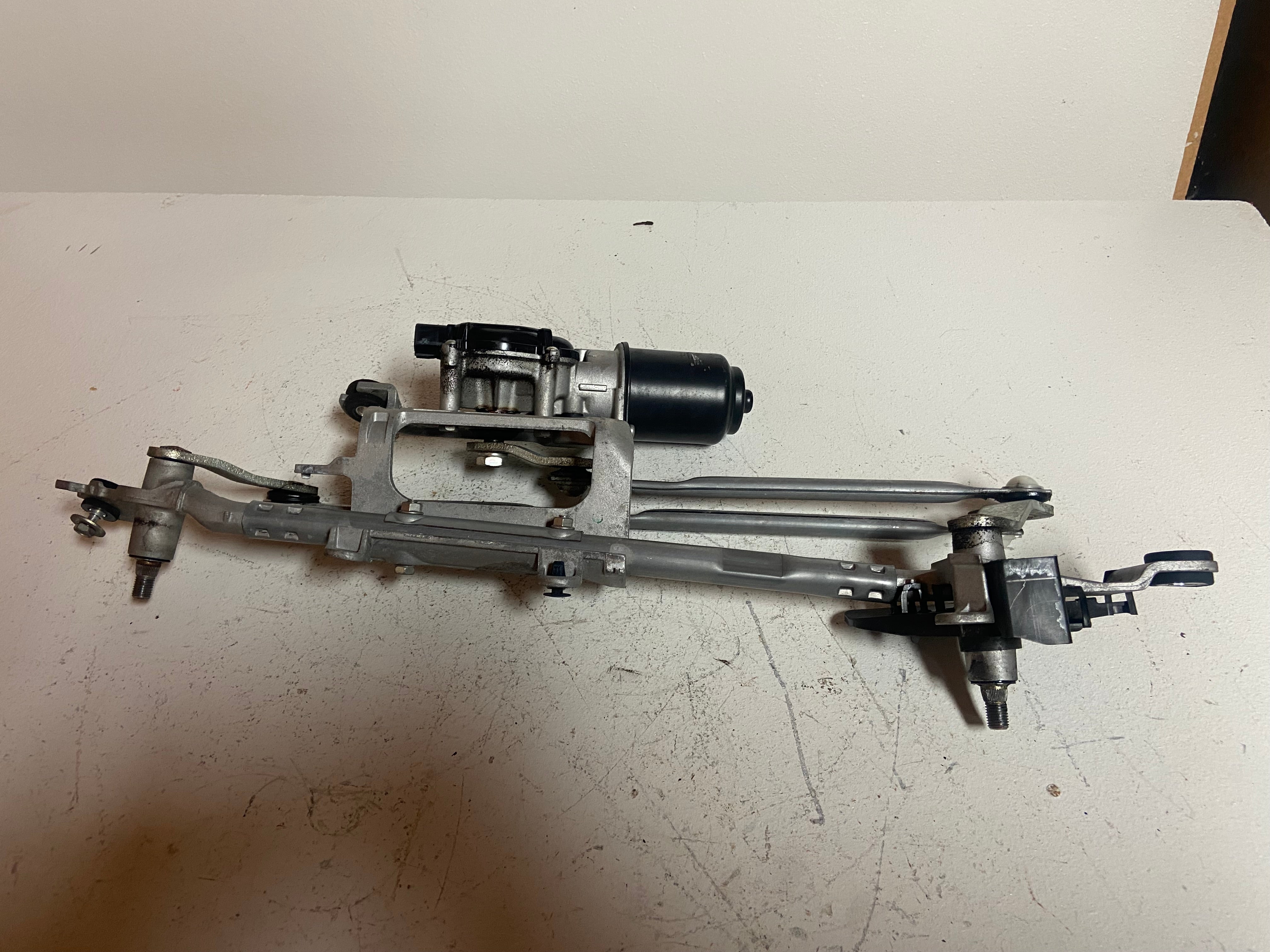 Windshield wiper motor and linkage assembly with long silver arms and brackets