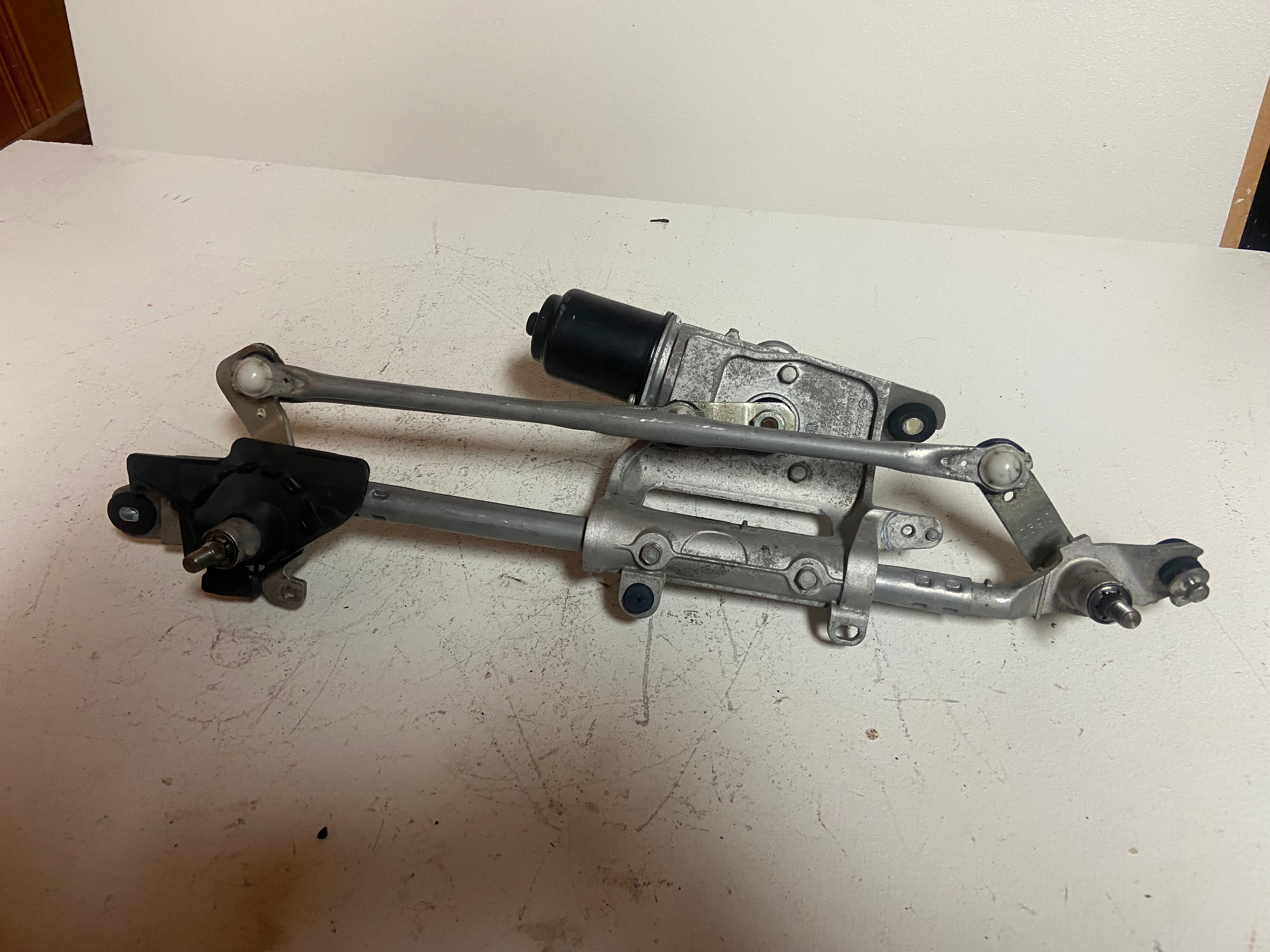 Windshield wiper motor and linkage assembly with metal arms and black actuator