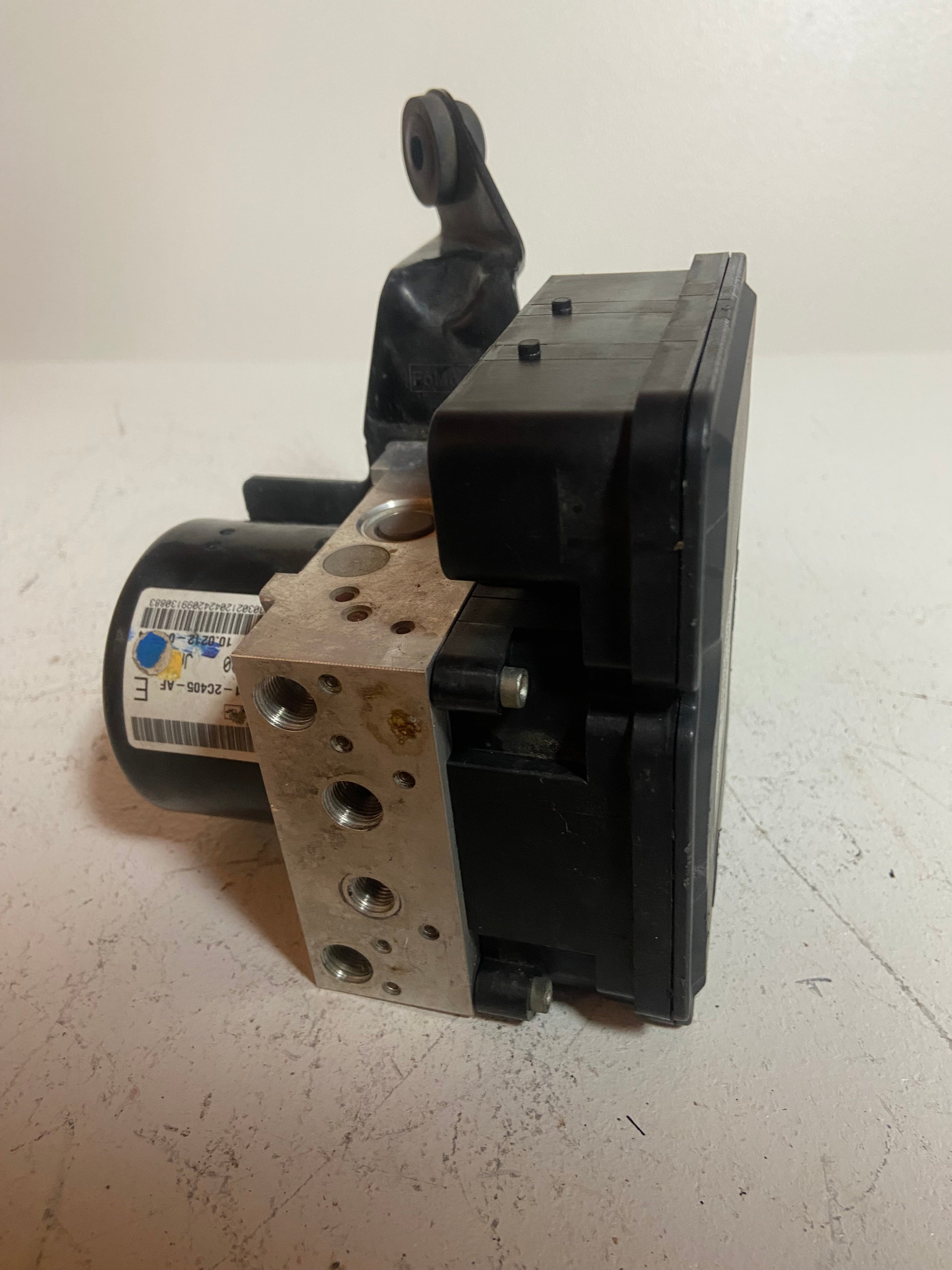 ABS brake pump control module with metal mounting plate and black electronics case.