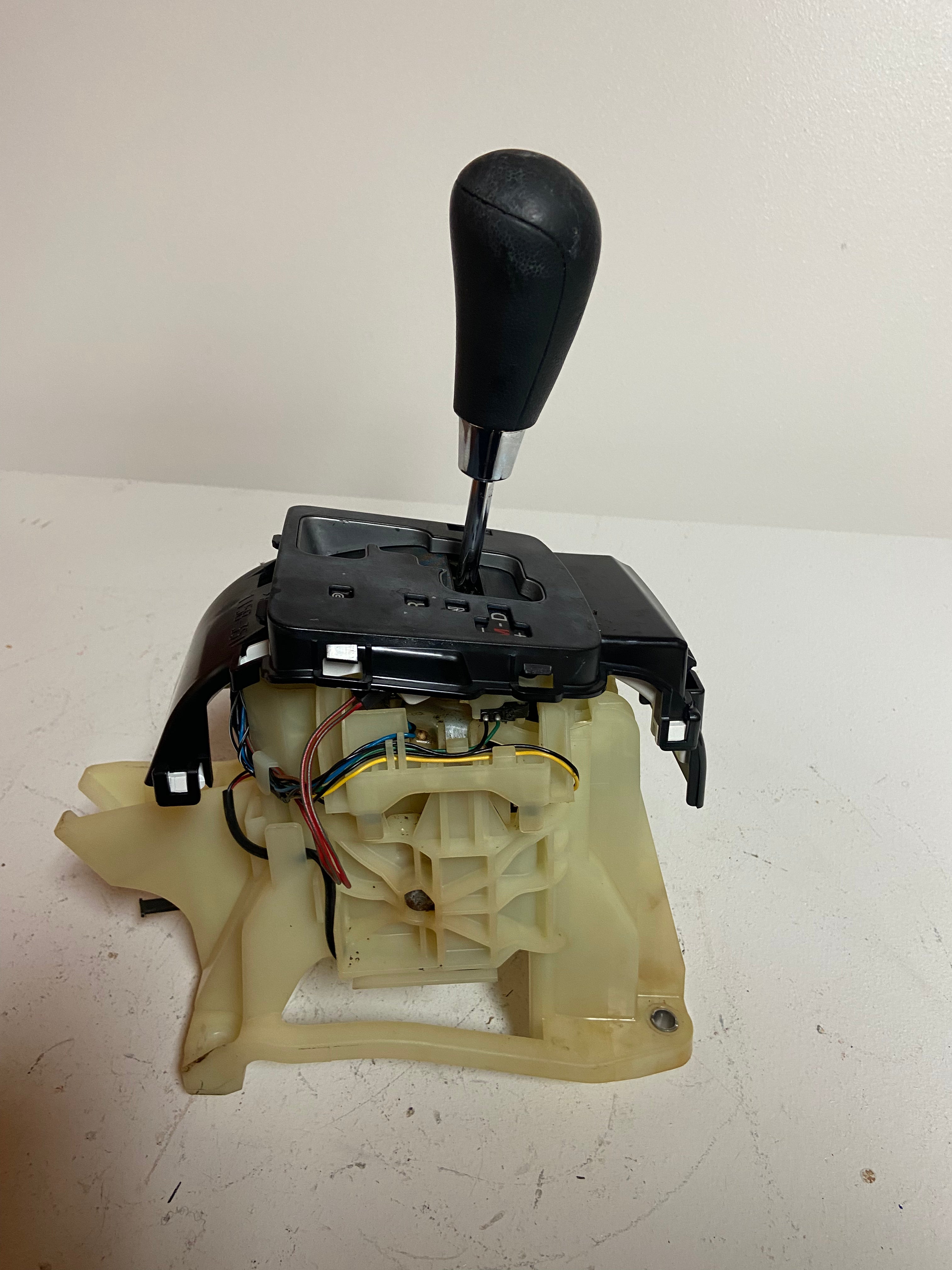 Automatic transmission shifter assembly with open beige housing and visible wiring
