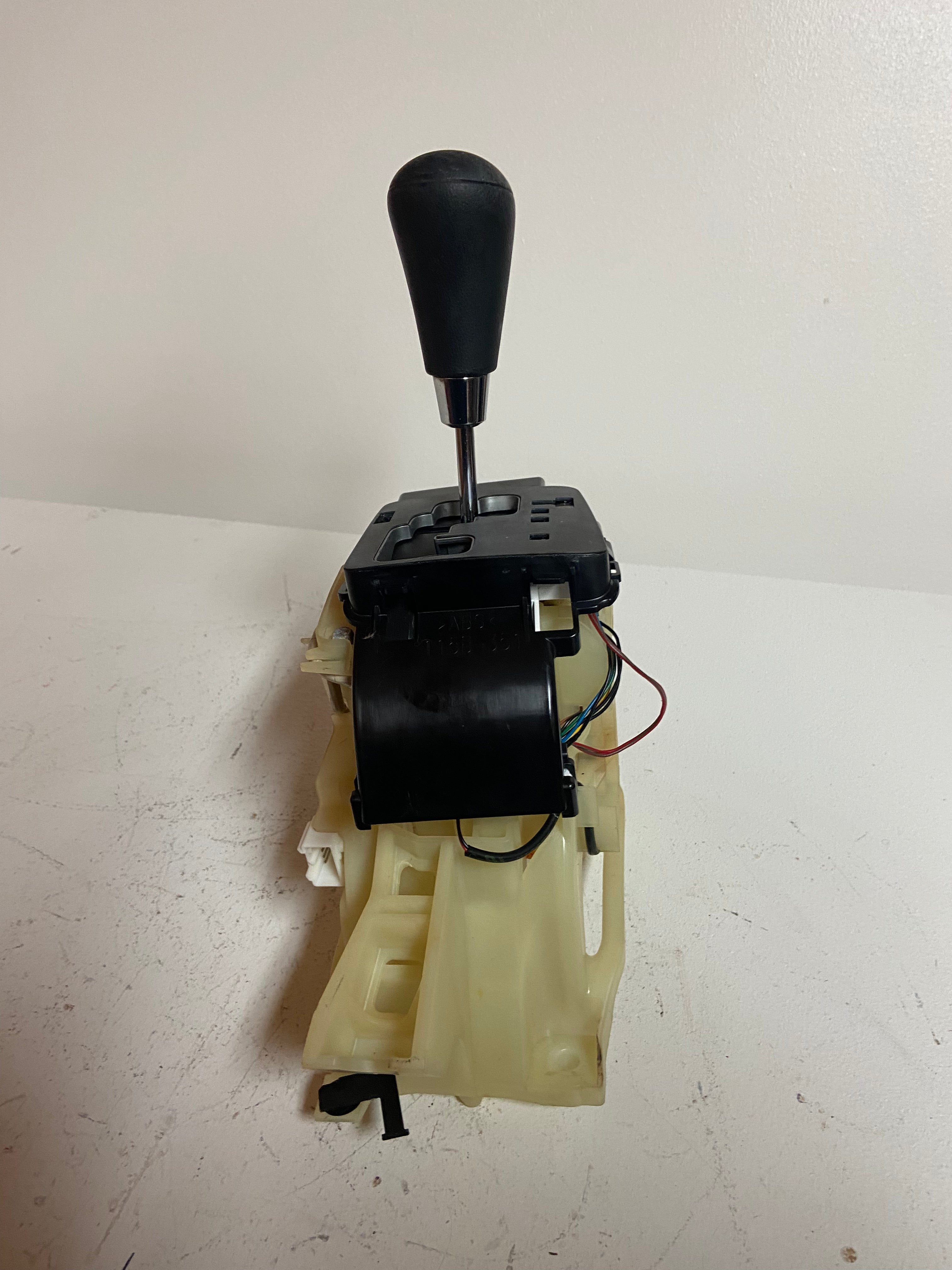 Automatic transmission shifter with black housing, beige base, and shift lever