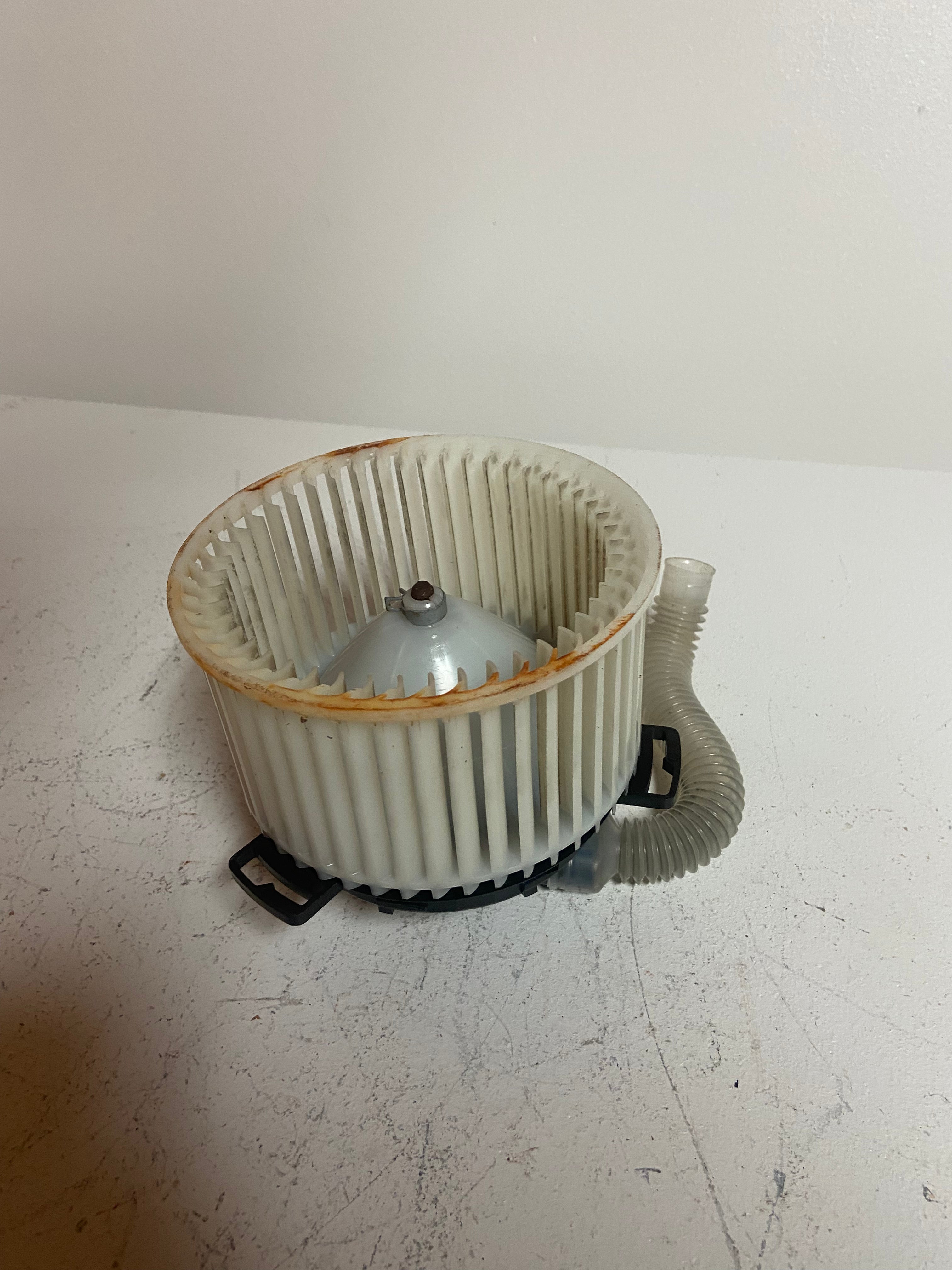 A/C heater blower motor with white fan housing and outlet hose