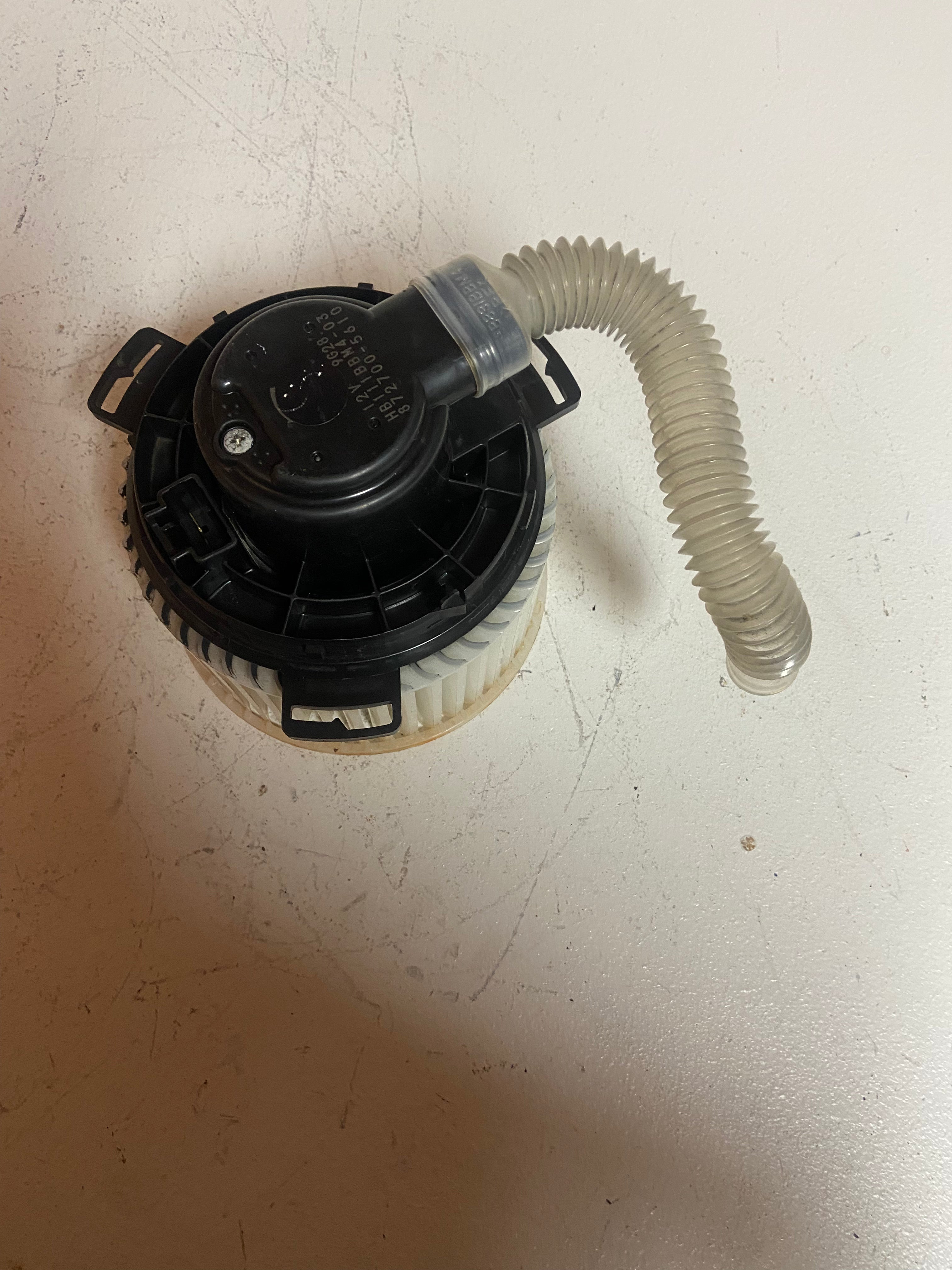 A/C heater blower motor with black housing and white corrugated duct