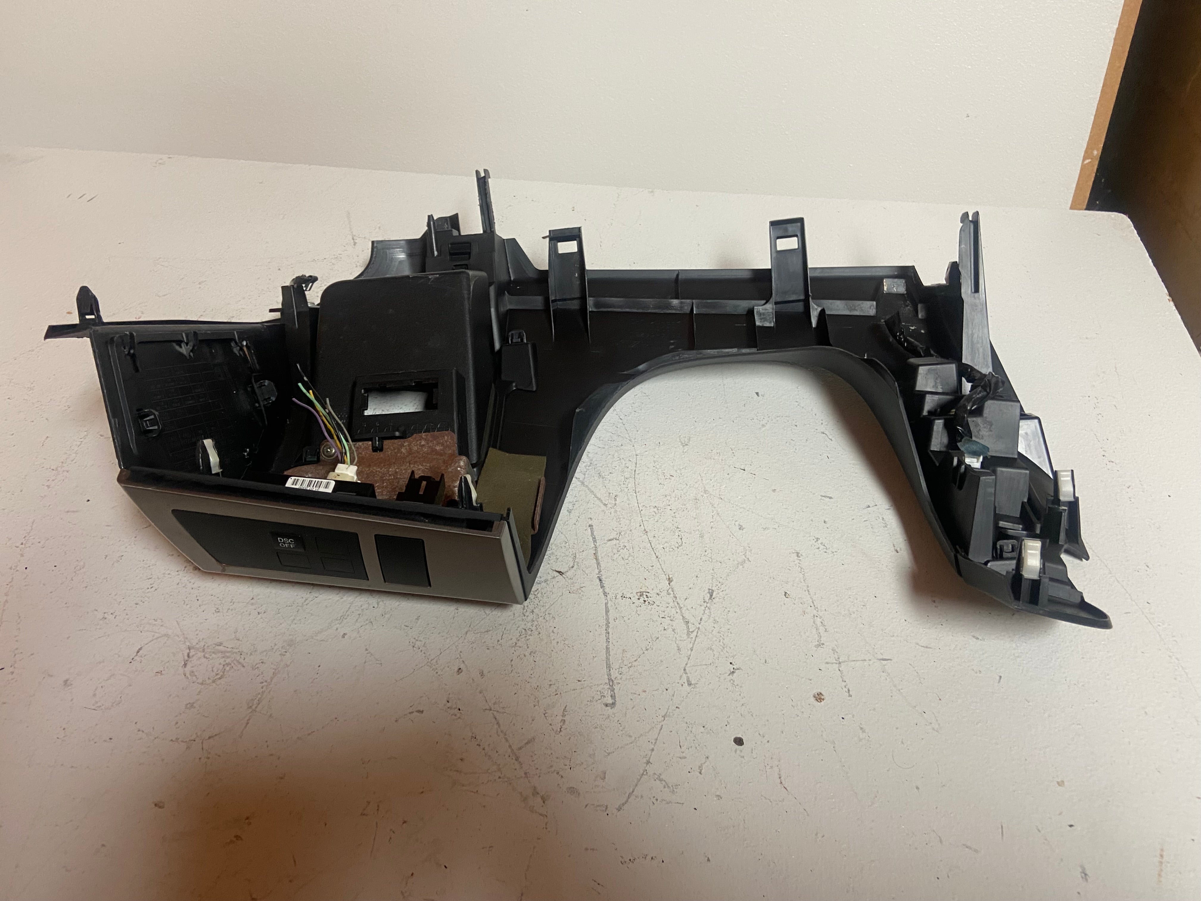 Black plastic dash trim assembly with mounting brackets and clips