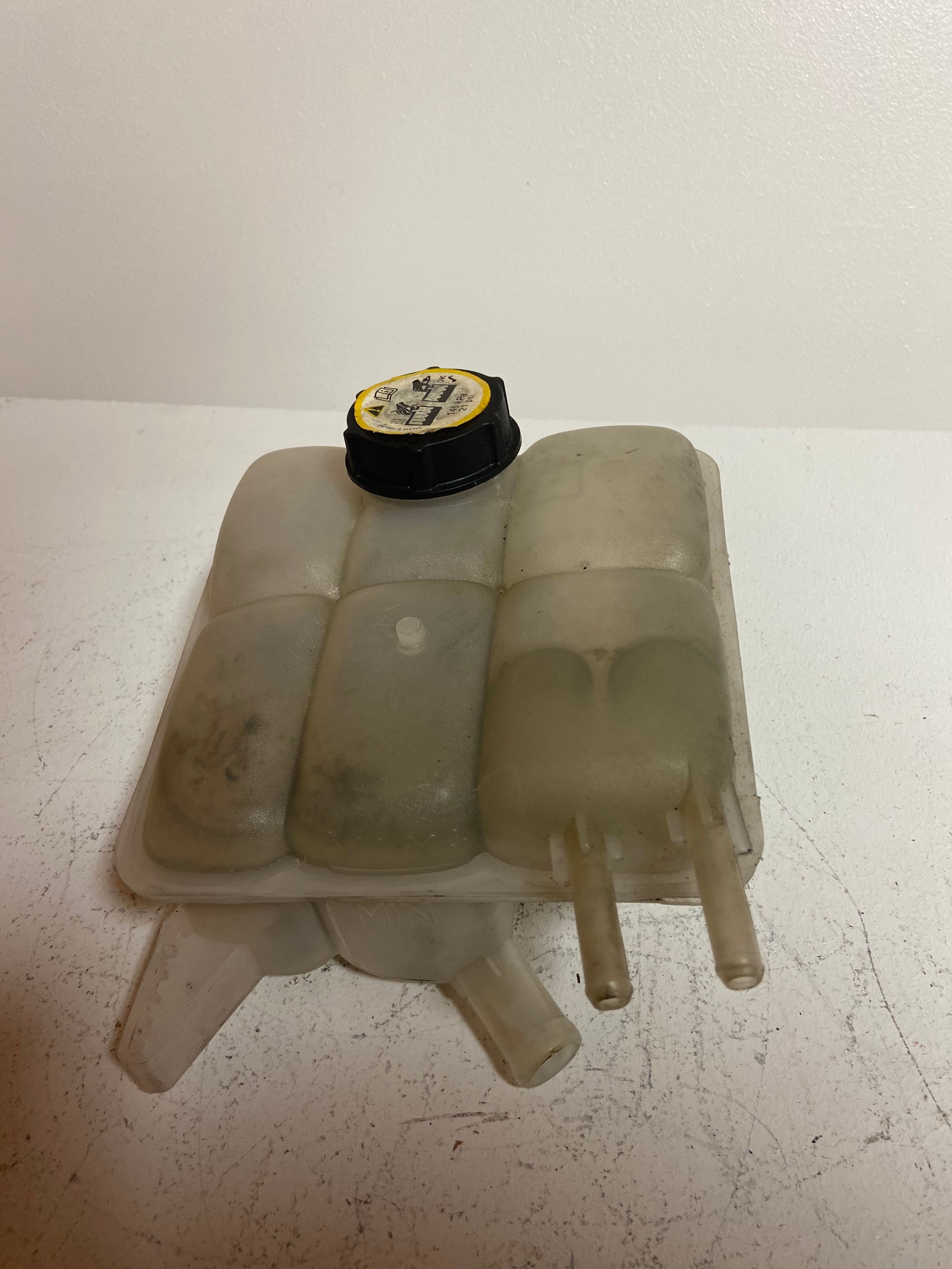 Engine coolant reservoir tank with black cap and molded plastic tank compartments