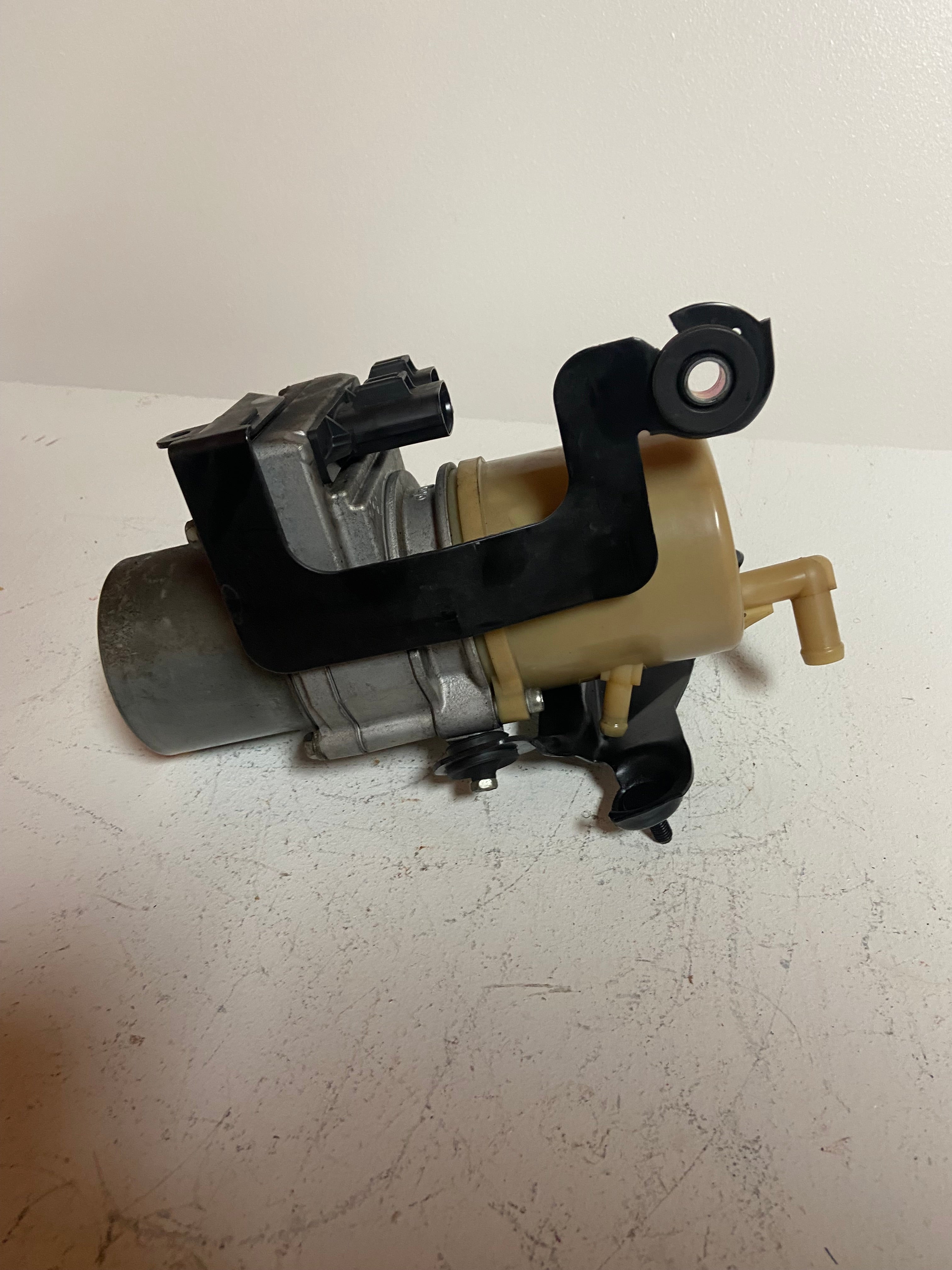 Power steering pump assembly with beige reservoir and black mounting arm