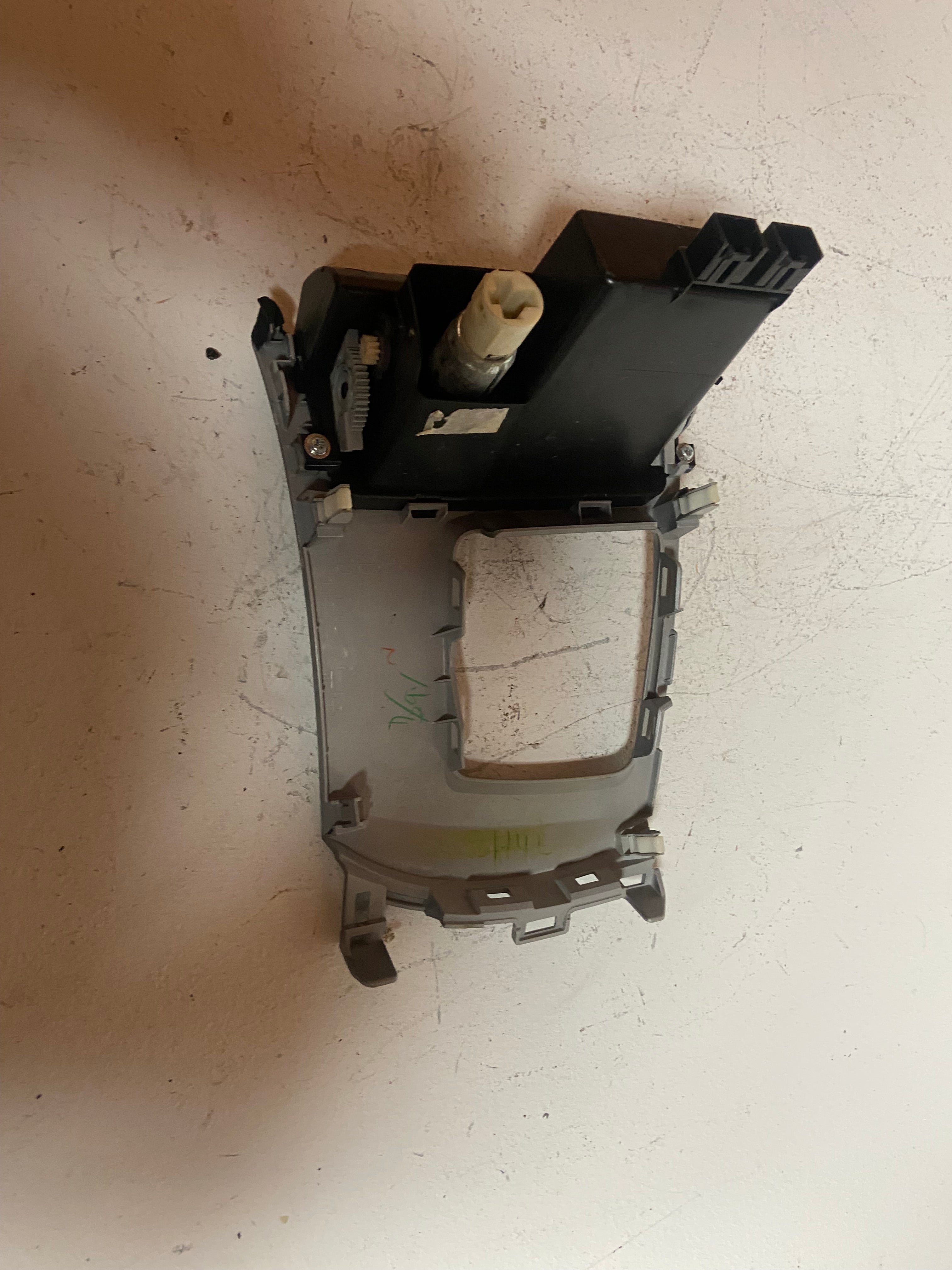 Shifter trim bezel bracket with black components and beige mounting insert