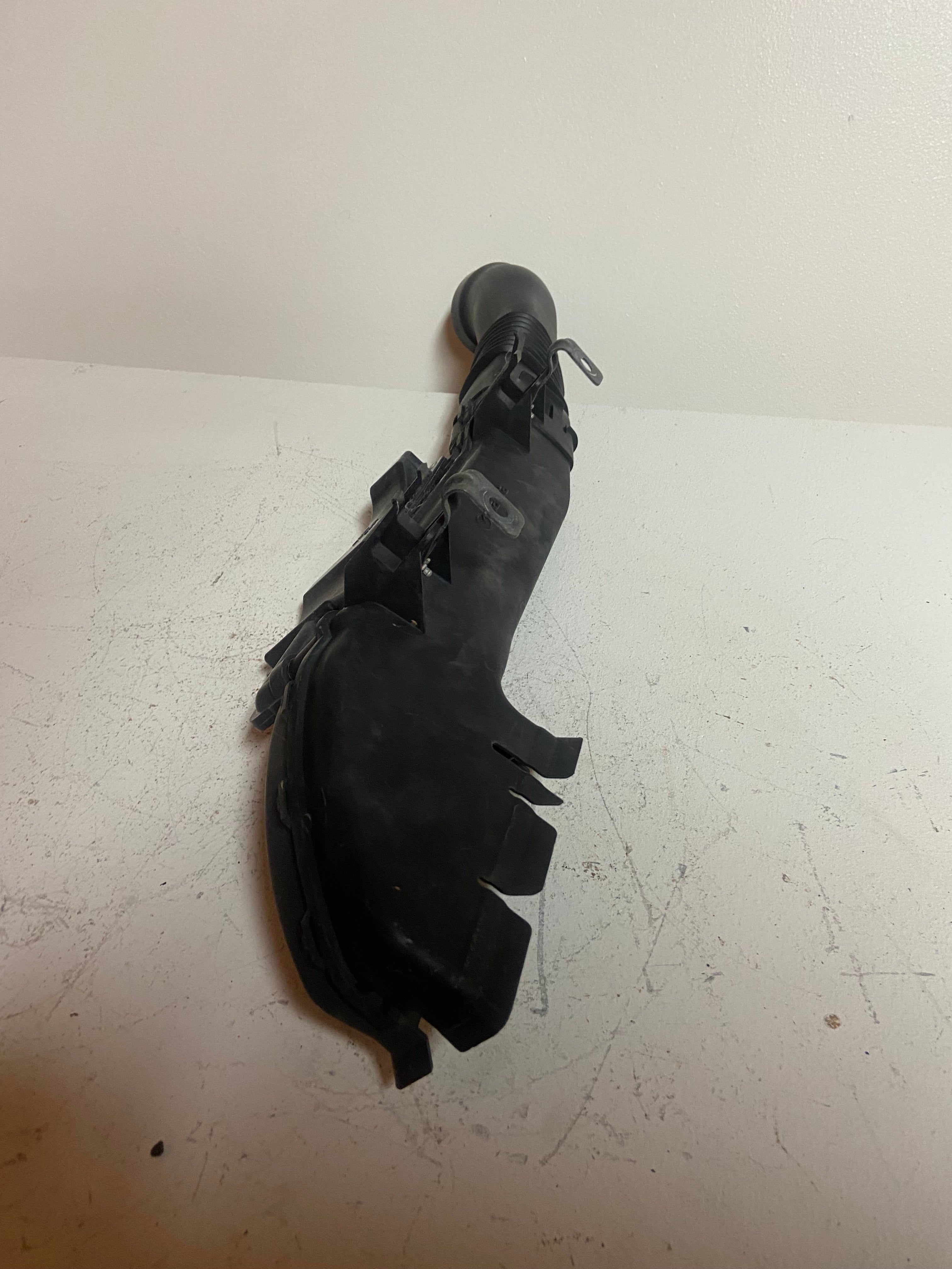 Black air intake duct housing with clip mounts and ribbed connector hose