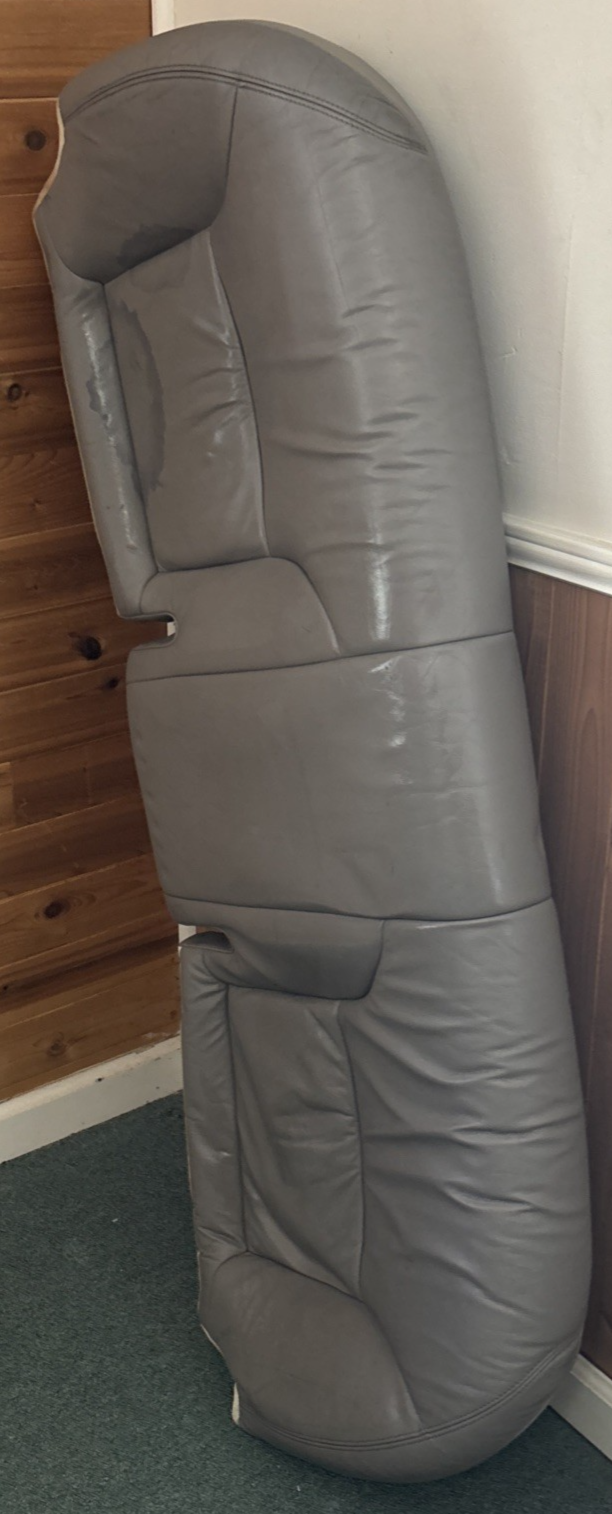 Gray sofa against a wooden wall and white baseboard.