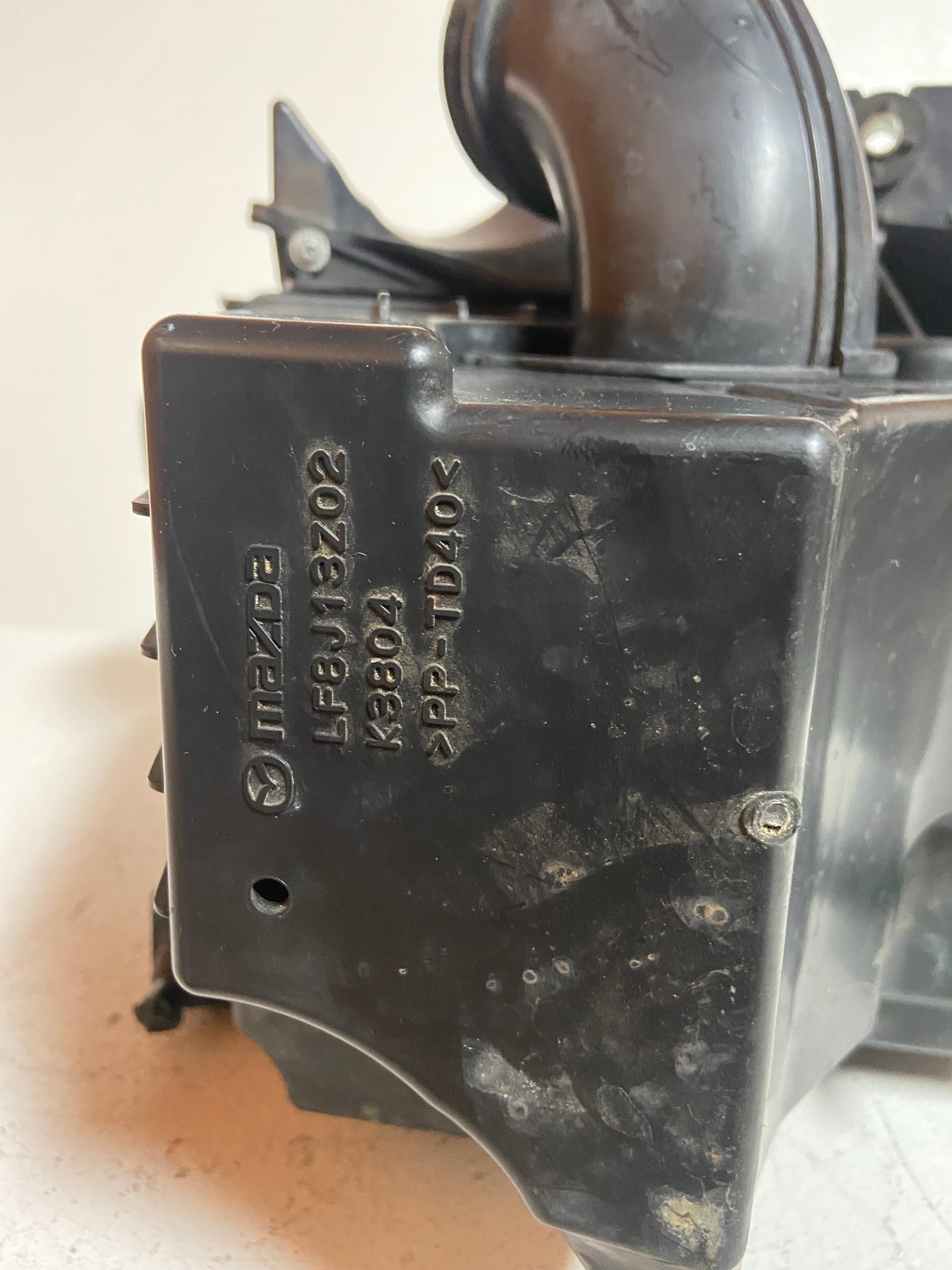 Air intake filter housing with molded Mazda part code and connector port