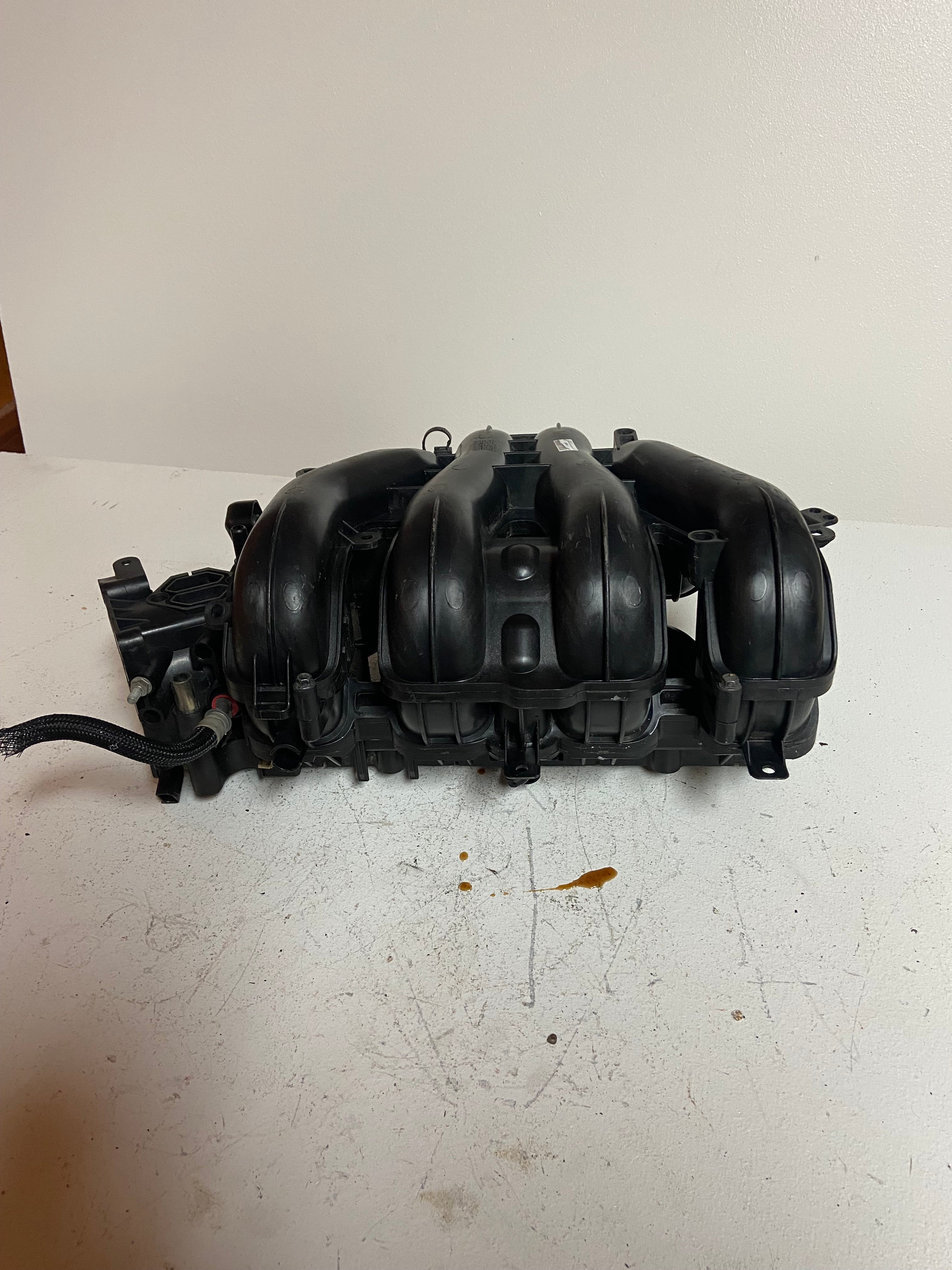 Engine air intake manifold with curved black intake runners and sensor housings