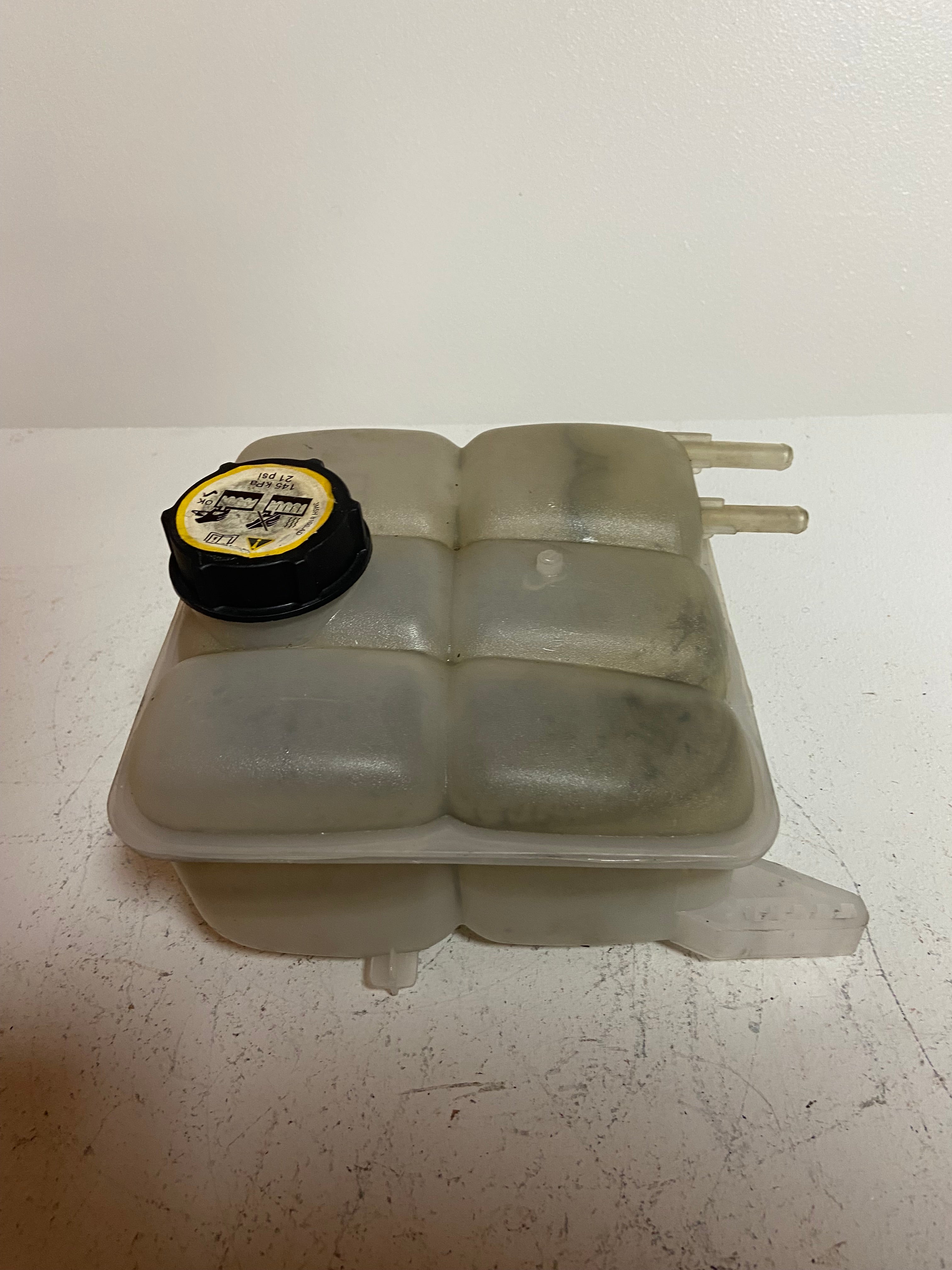 Engine coolant reservoir tank with black cap and two connected outlet tubes