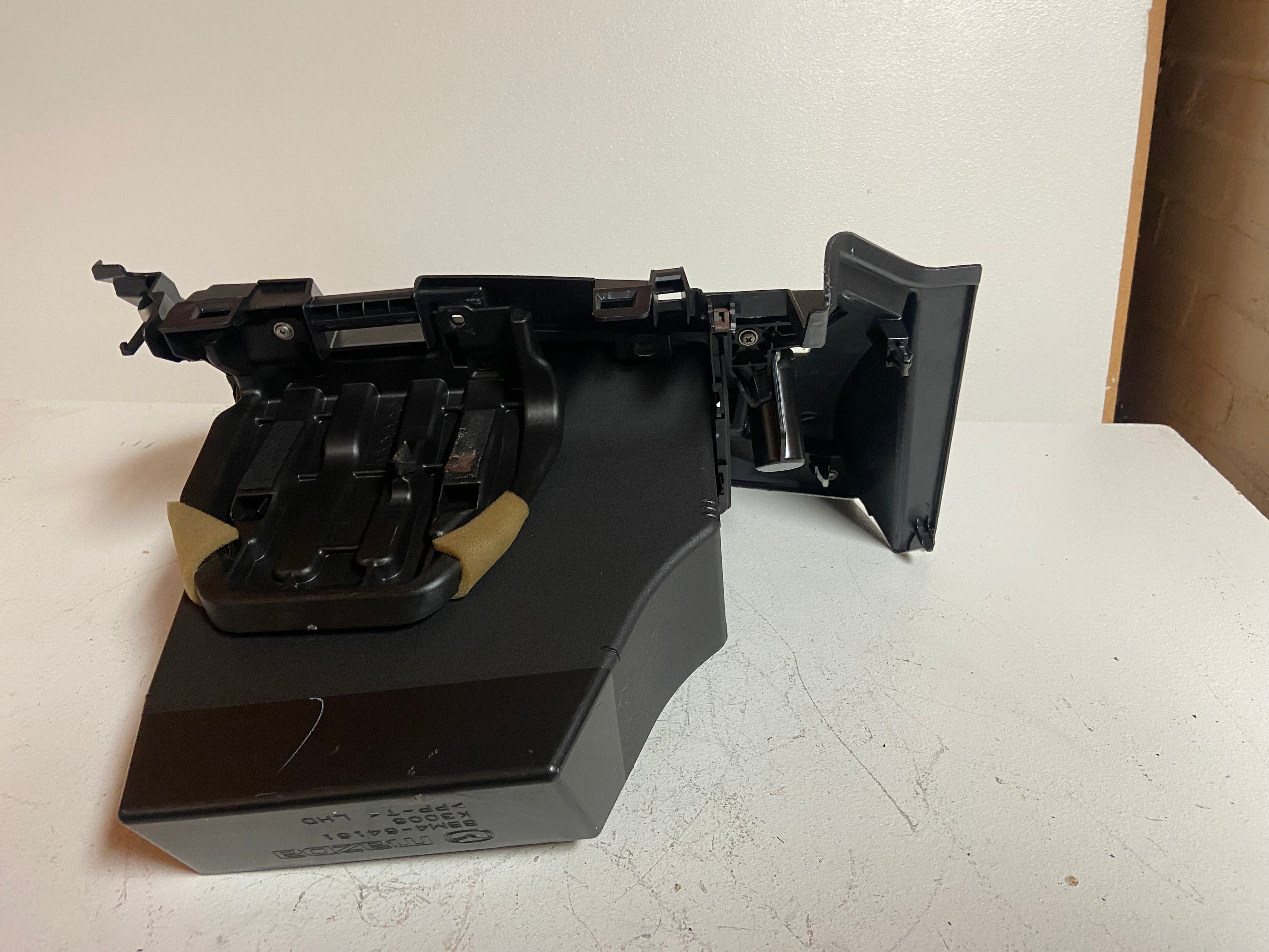 Black glove box compartment assembly with hinged door and latch mechanism
