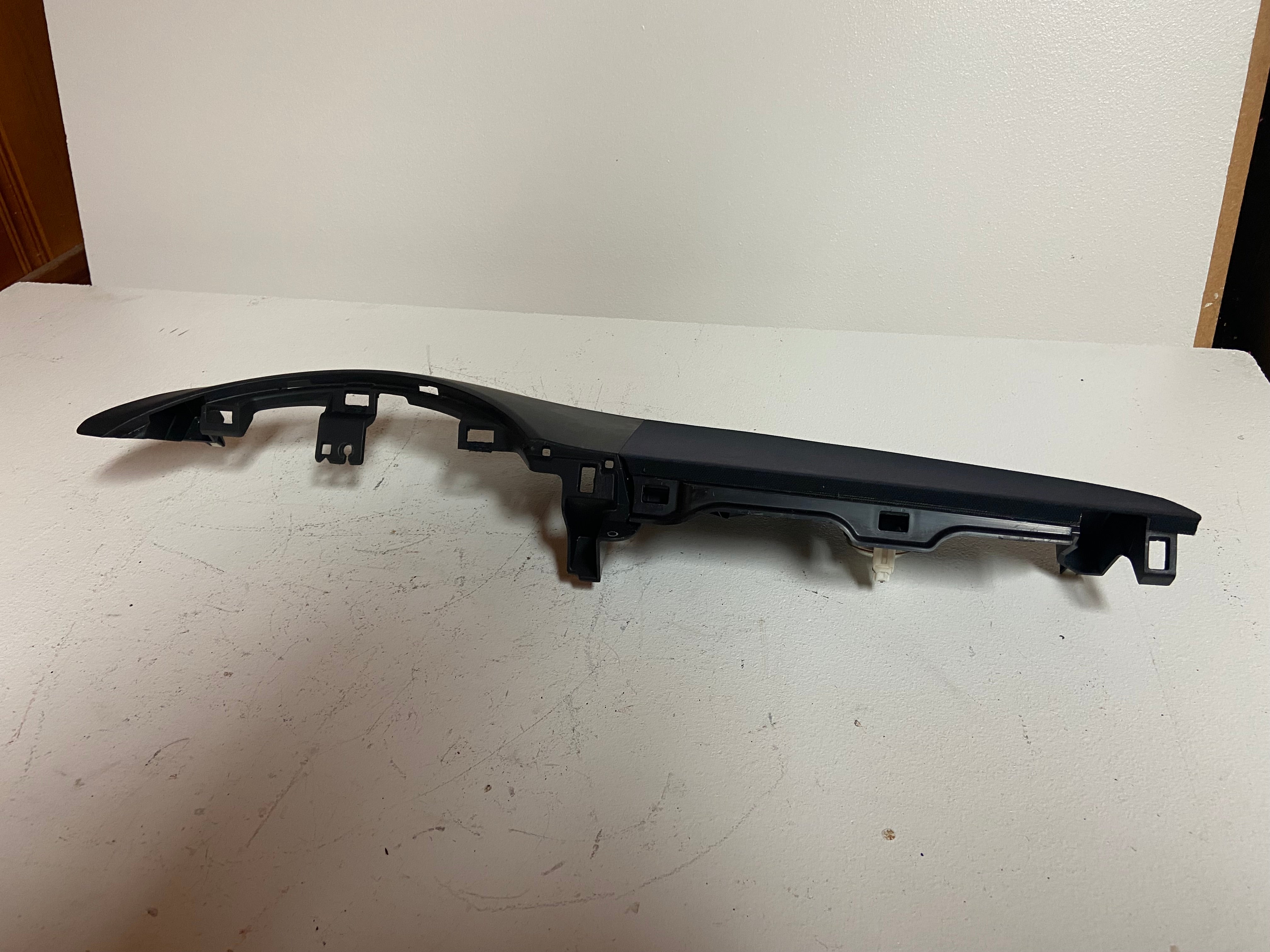 Long dark dash trim bezel with mounting holes and clip supports