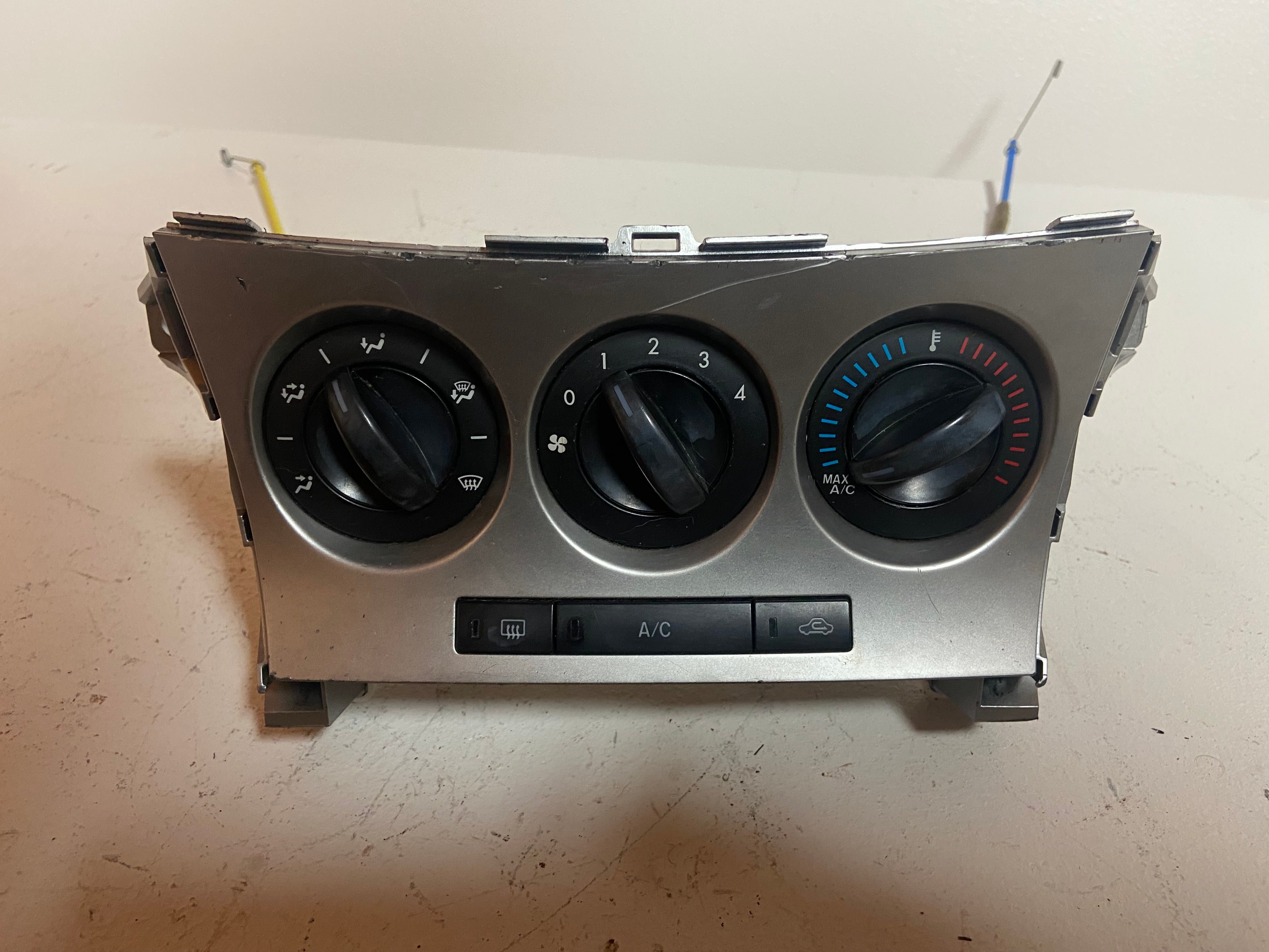Manual climate control panel with three knobs and blue A/C temperature scale