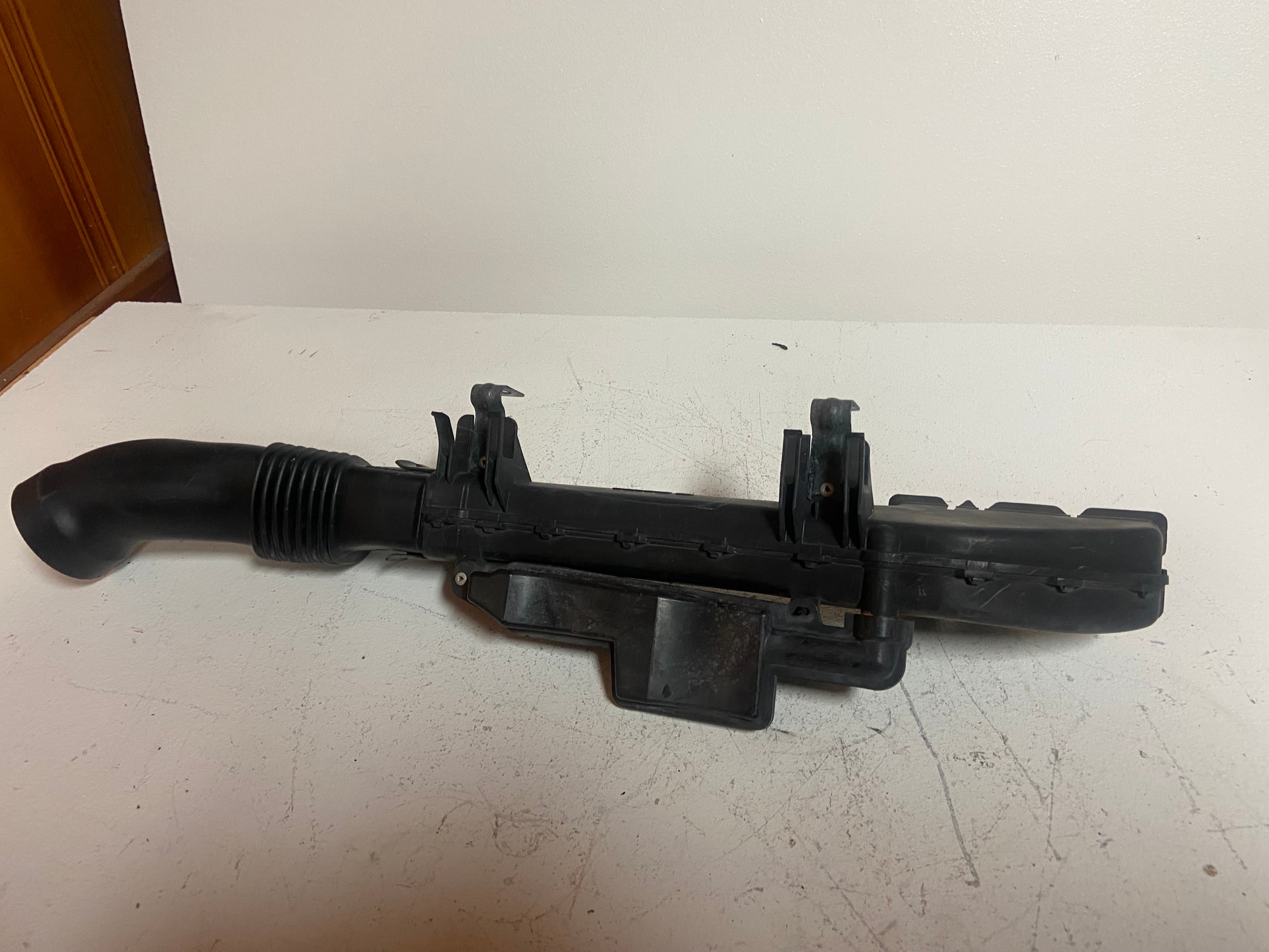 Black engine air intake duct with vented mounting panel and ribbed hose