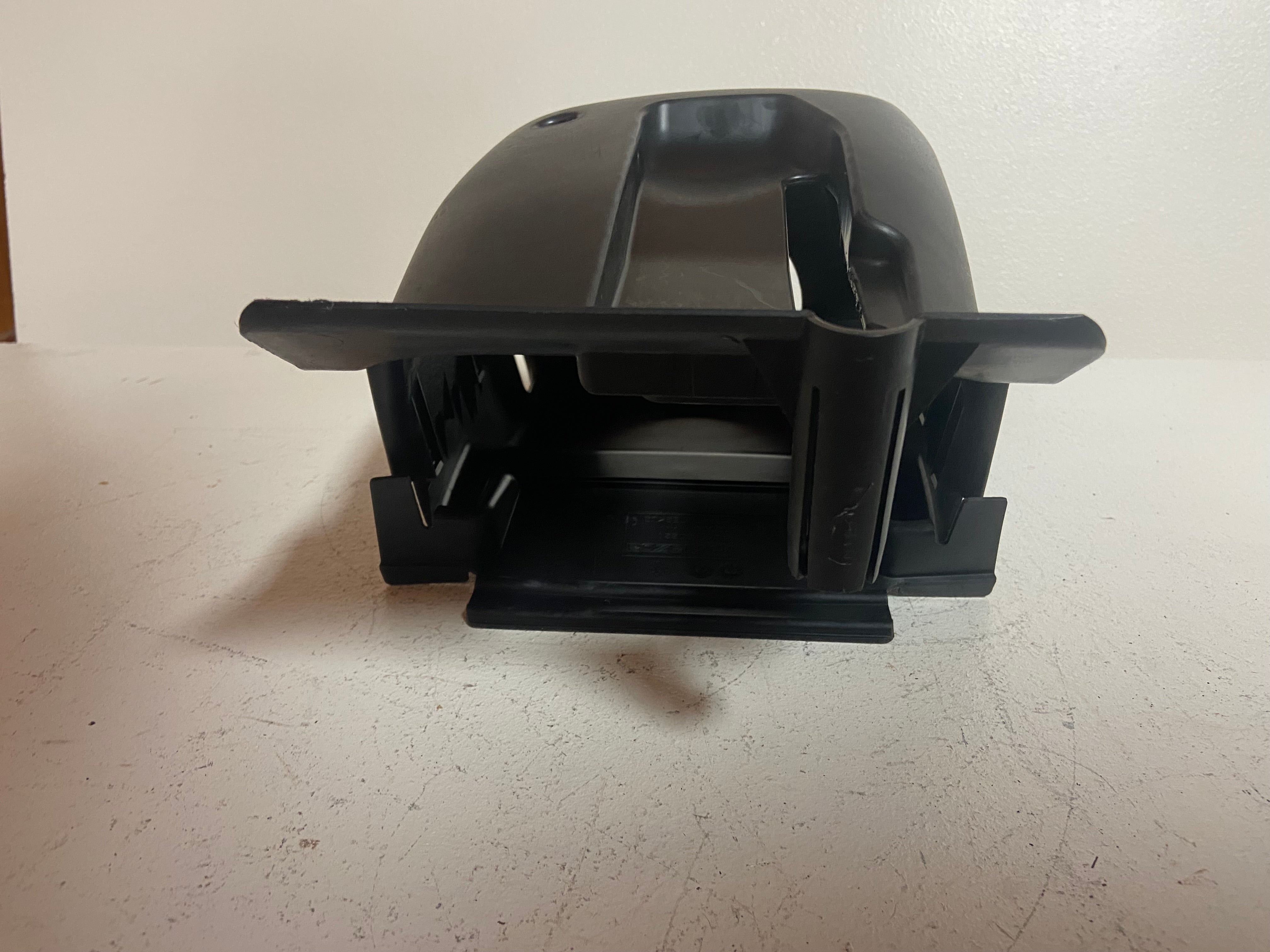 Black plastic steering column shroud cover, side view with mounting tabs