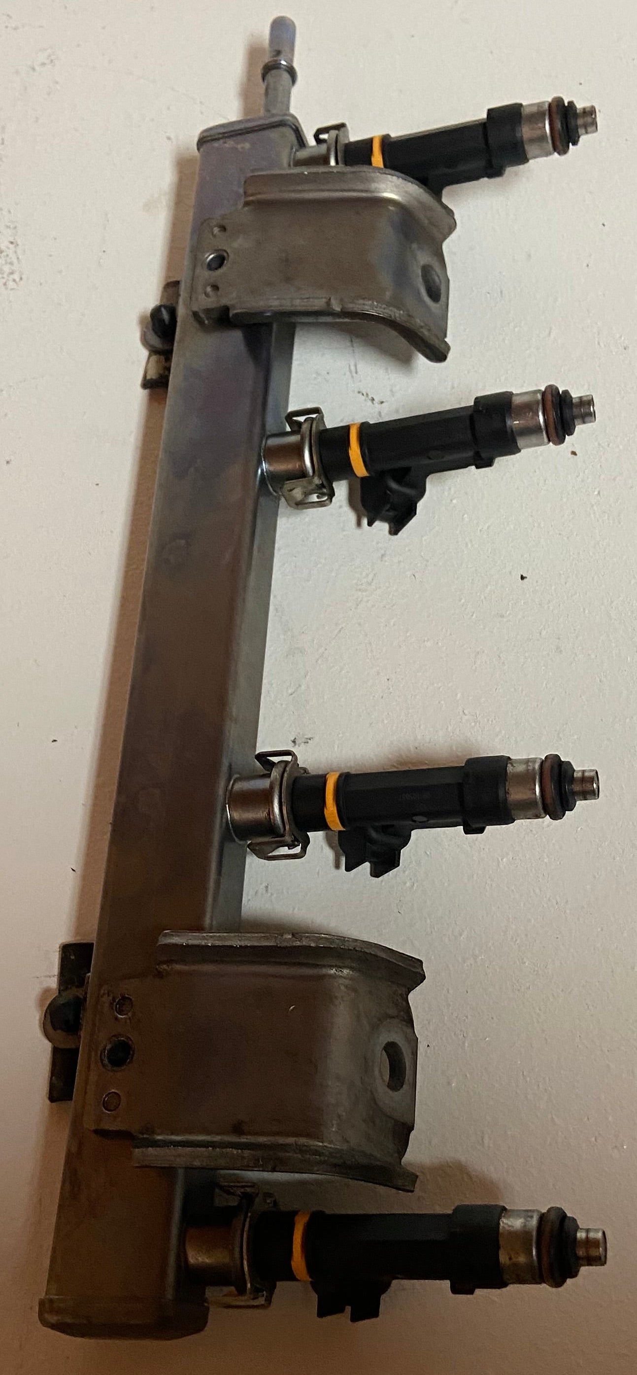 Engine fuel rail with four black injector connectors and mounting brackets