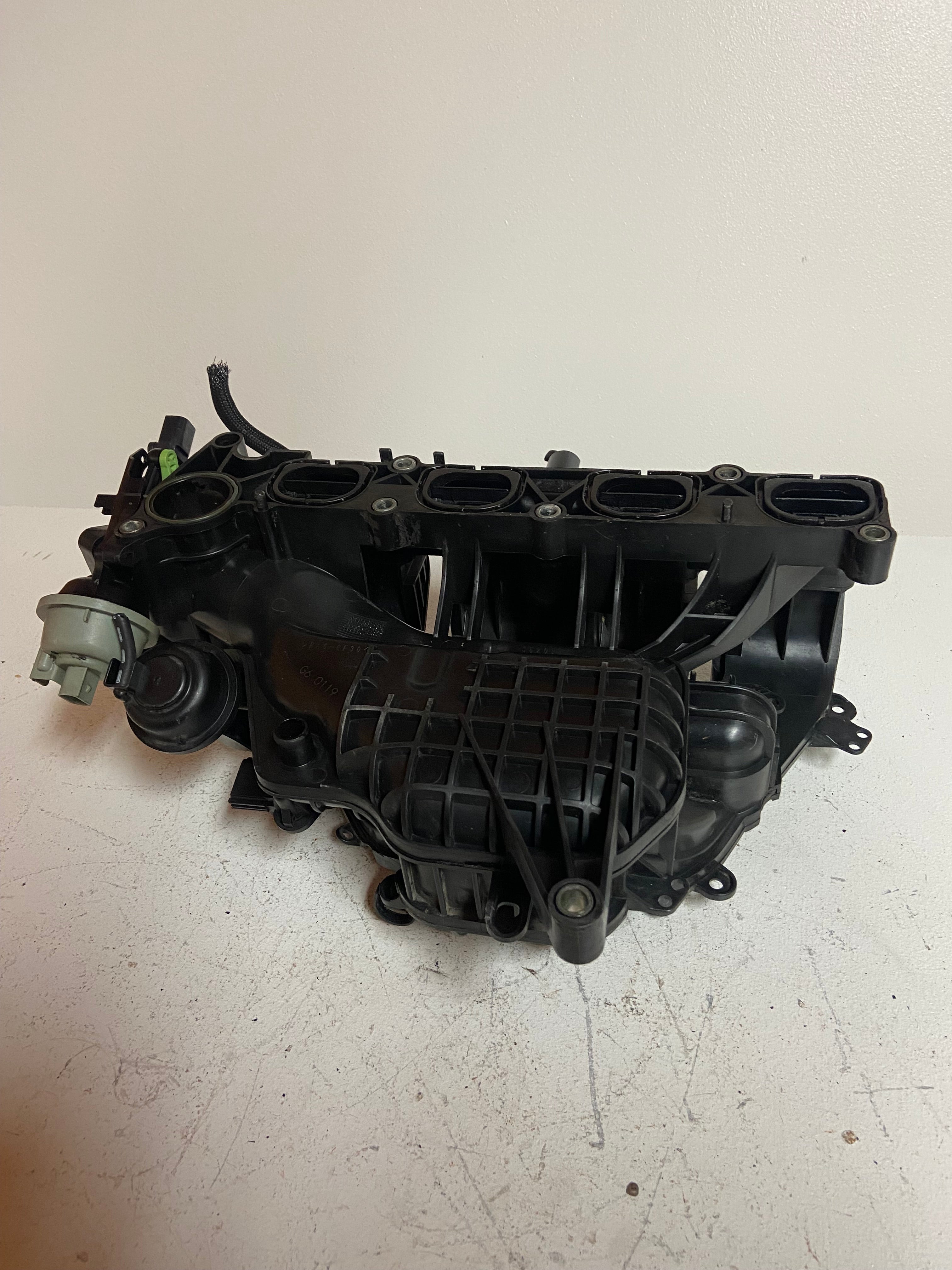 Engine air intake manifold with intake chamber ports and ribbed housing