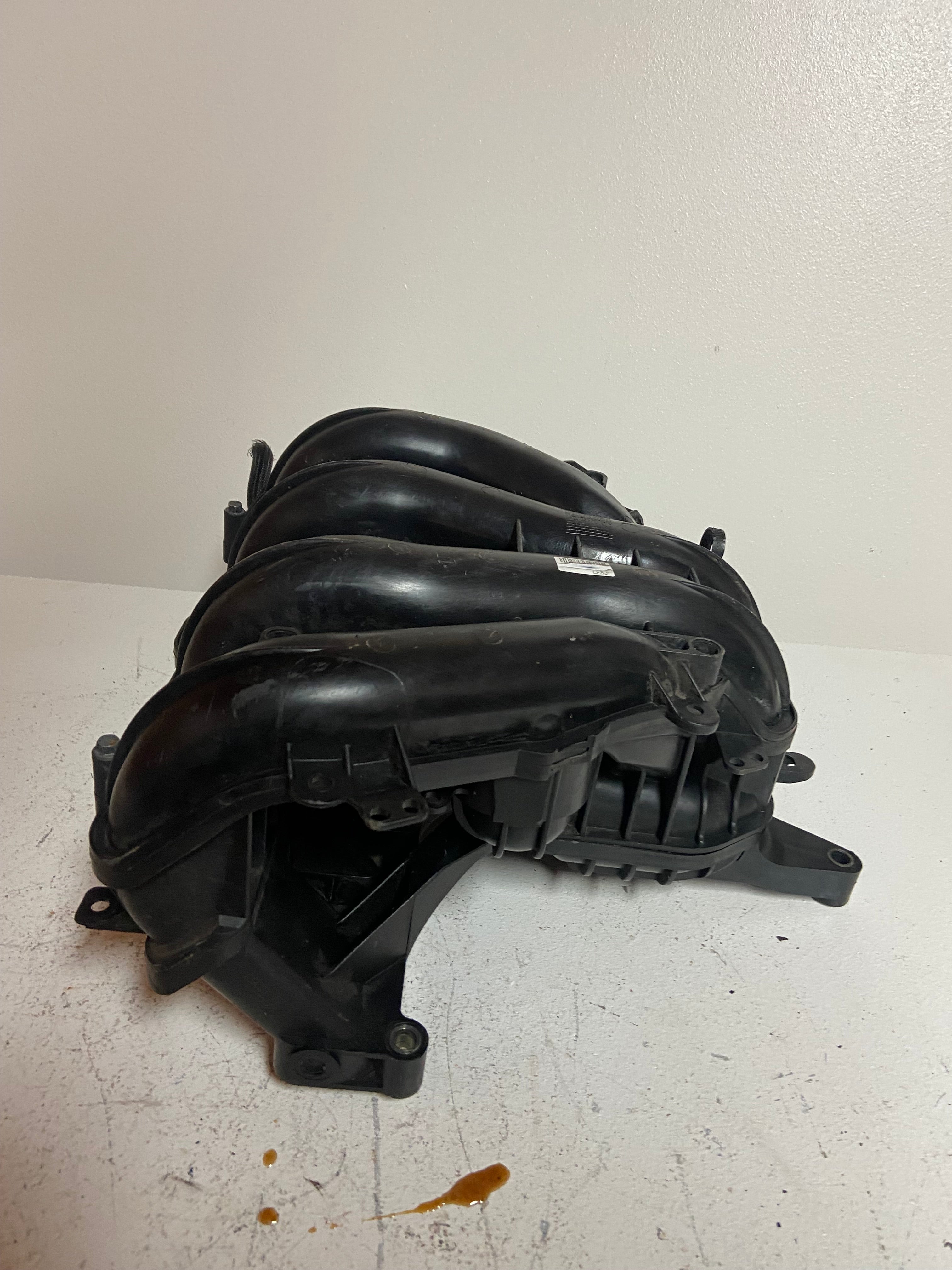 Engine air intake manifold showing ribbed black ducting and attachment tabs