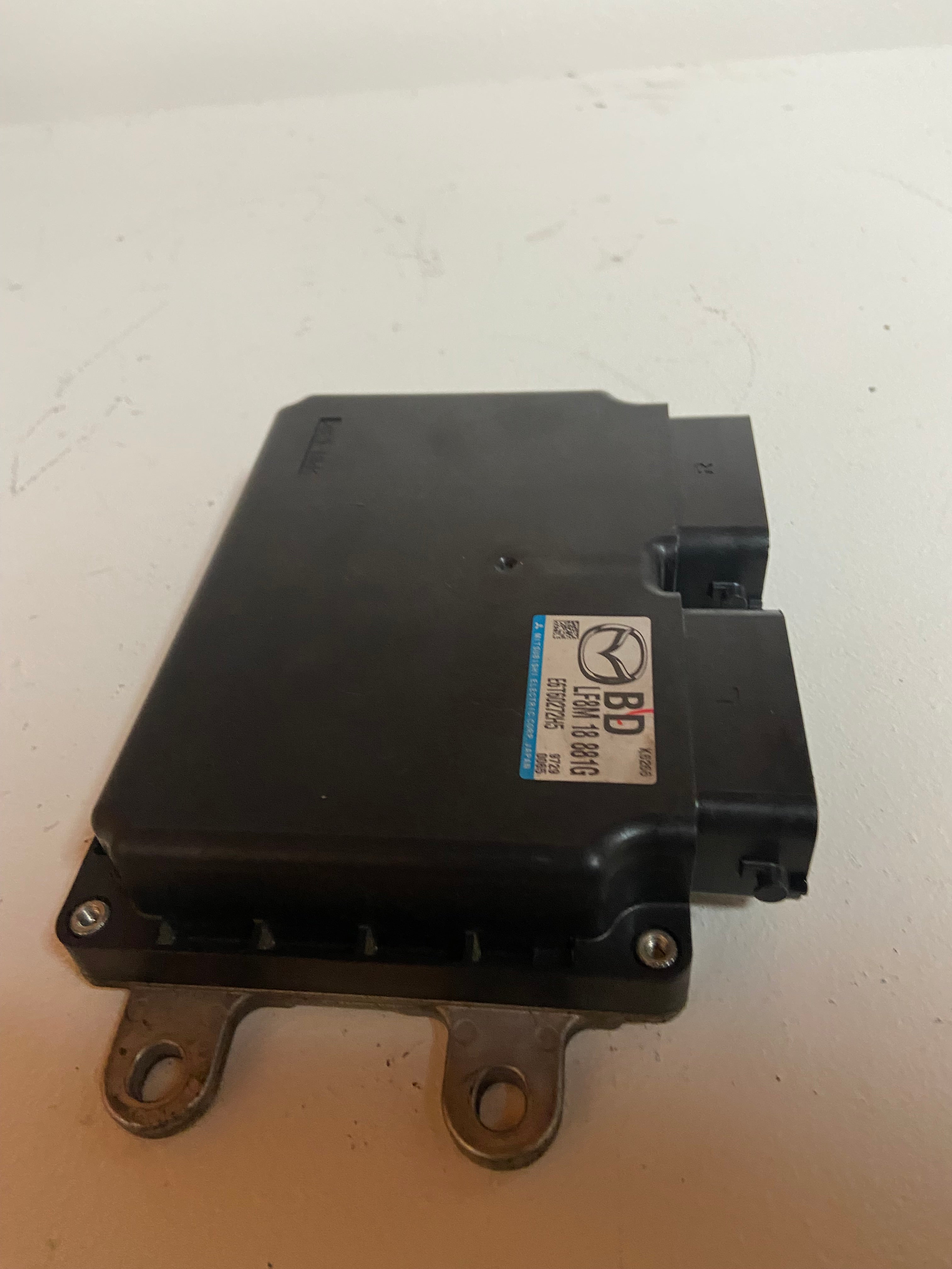 Black engine control module with blue label and four mounting feet