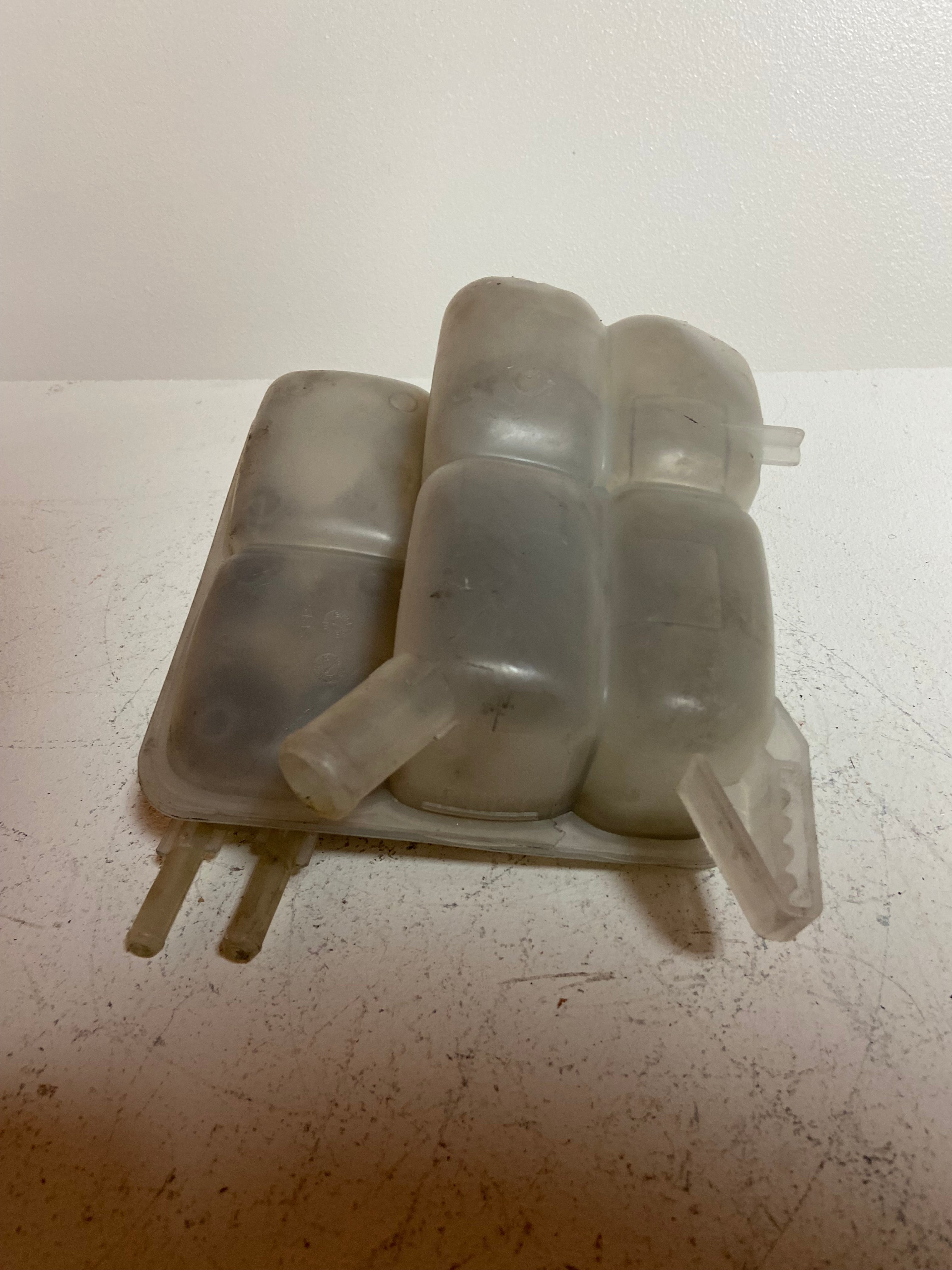 Engine coolant reservoir tank, light gray plastic with two mounting tabs and tubes