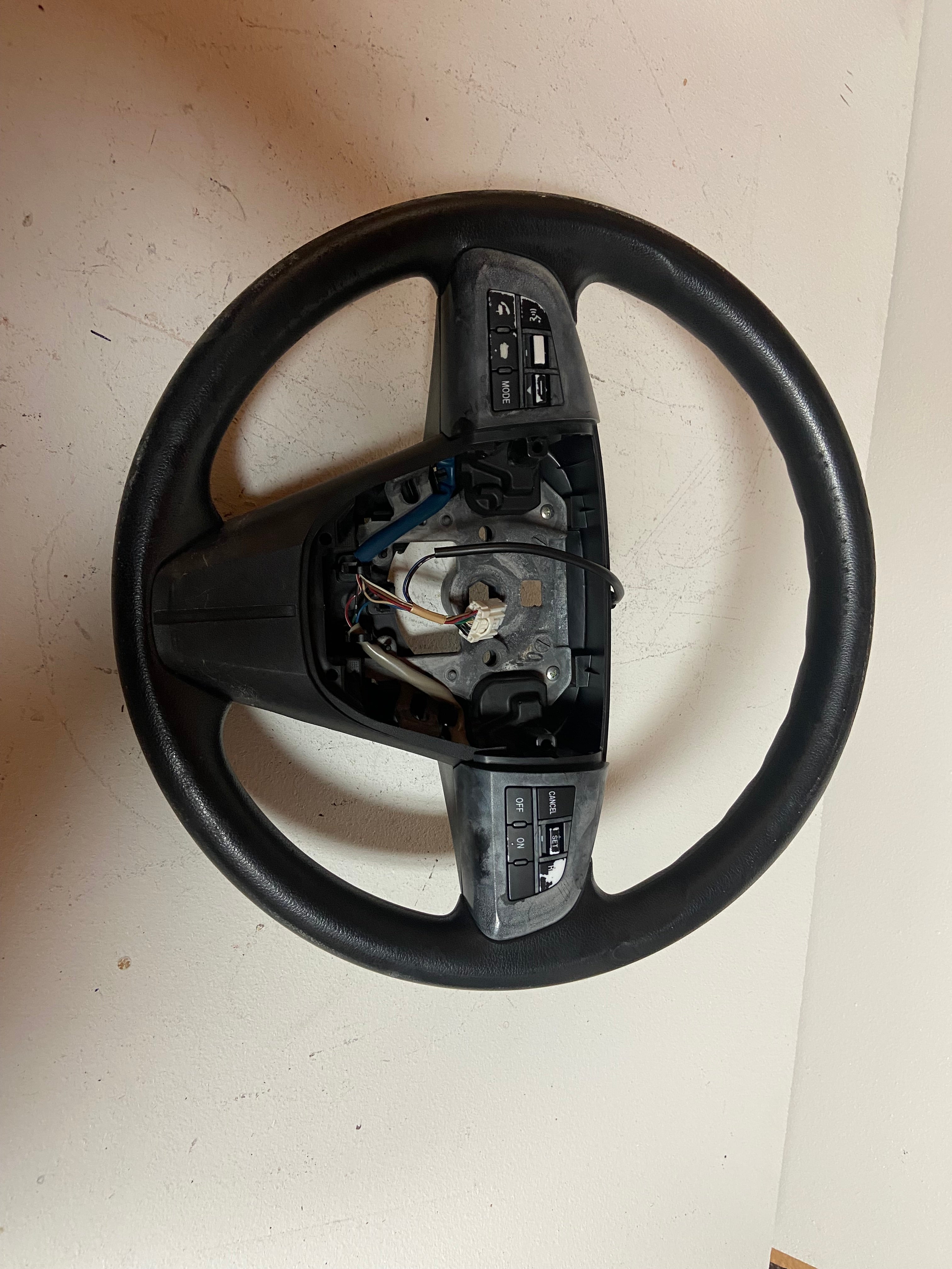 Black OEM steering wheel for 2010 Mazda 3 touring, close rear view with exposed assembly