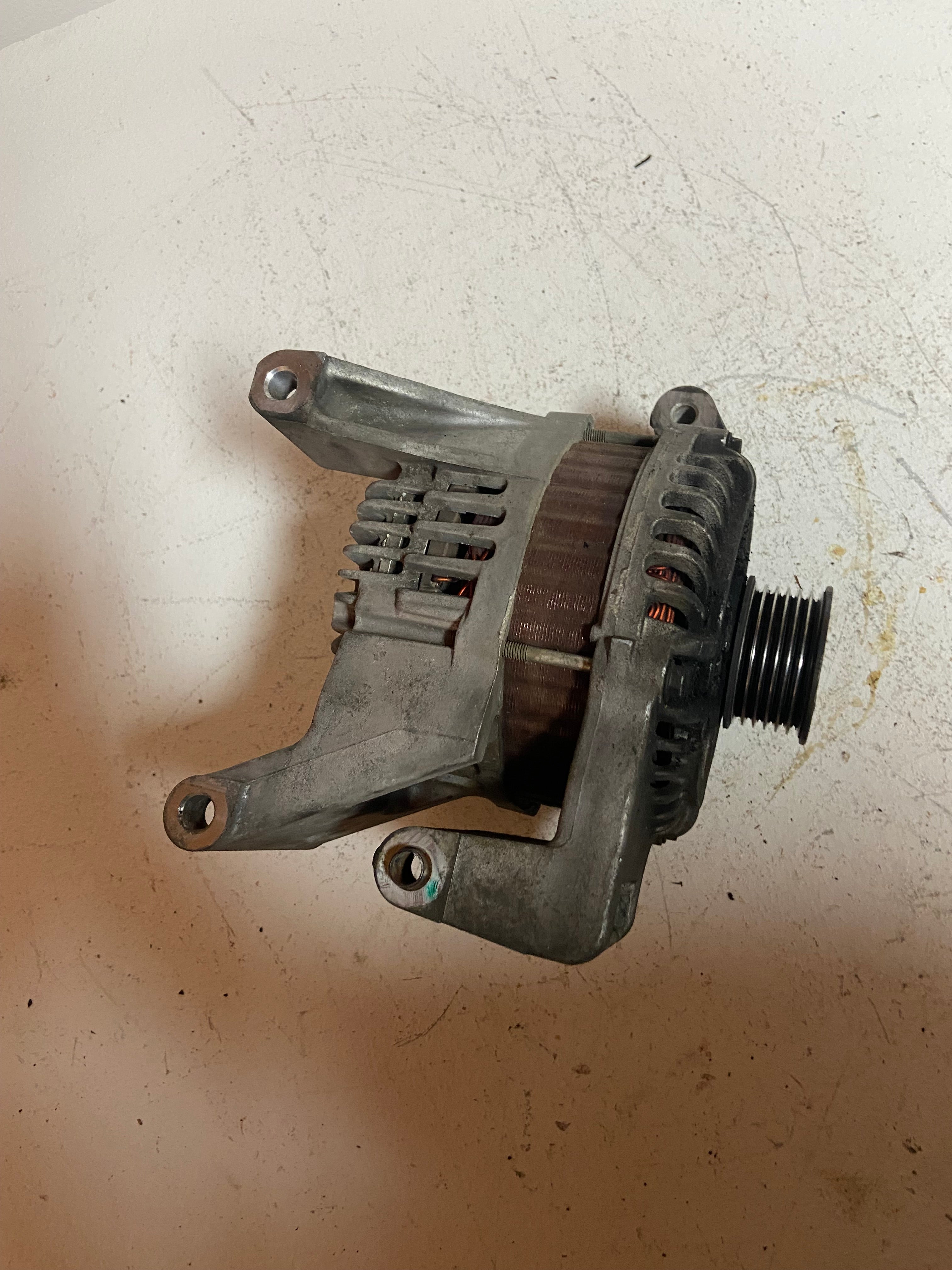 Gray alternator with belt pulley and finned rear housing, side brackets