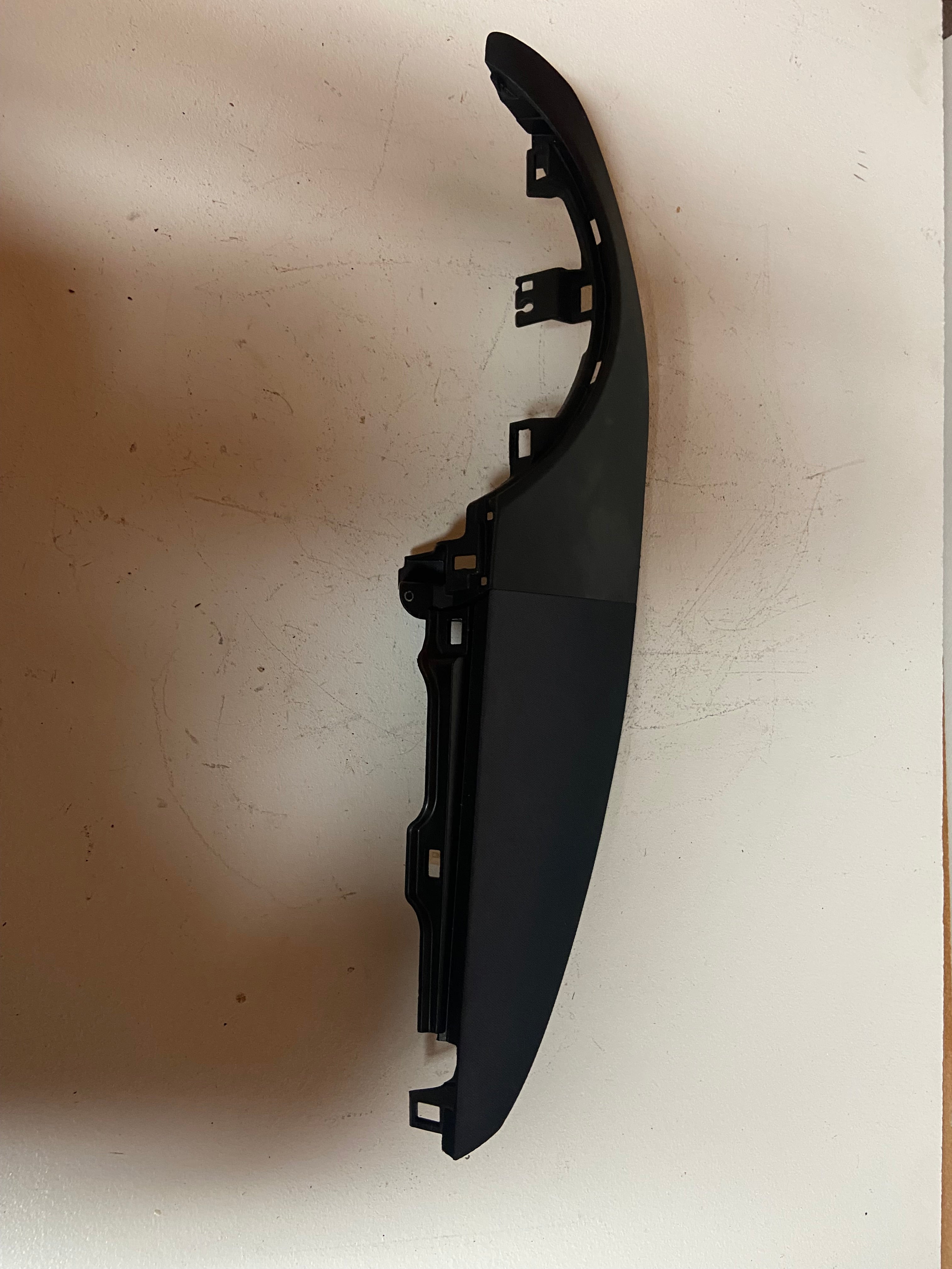 Side view of dark instrument cluster trim bezel with mounting brackets
